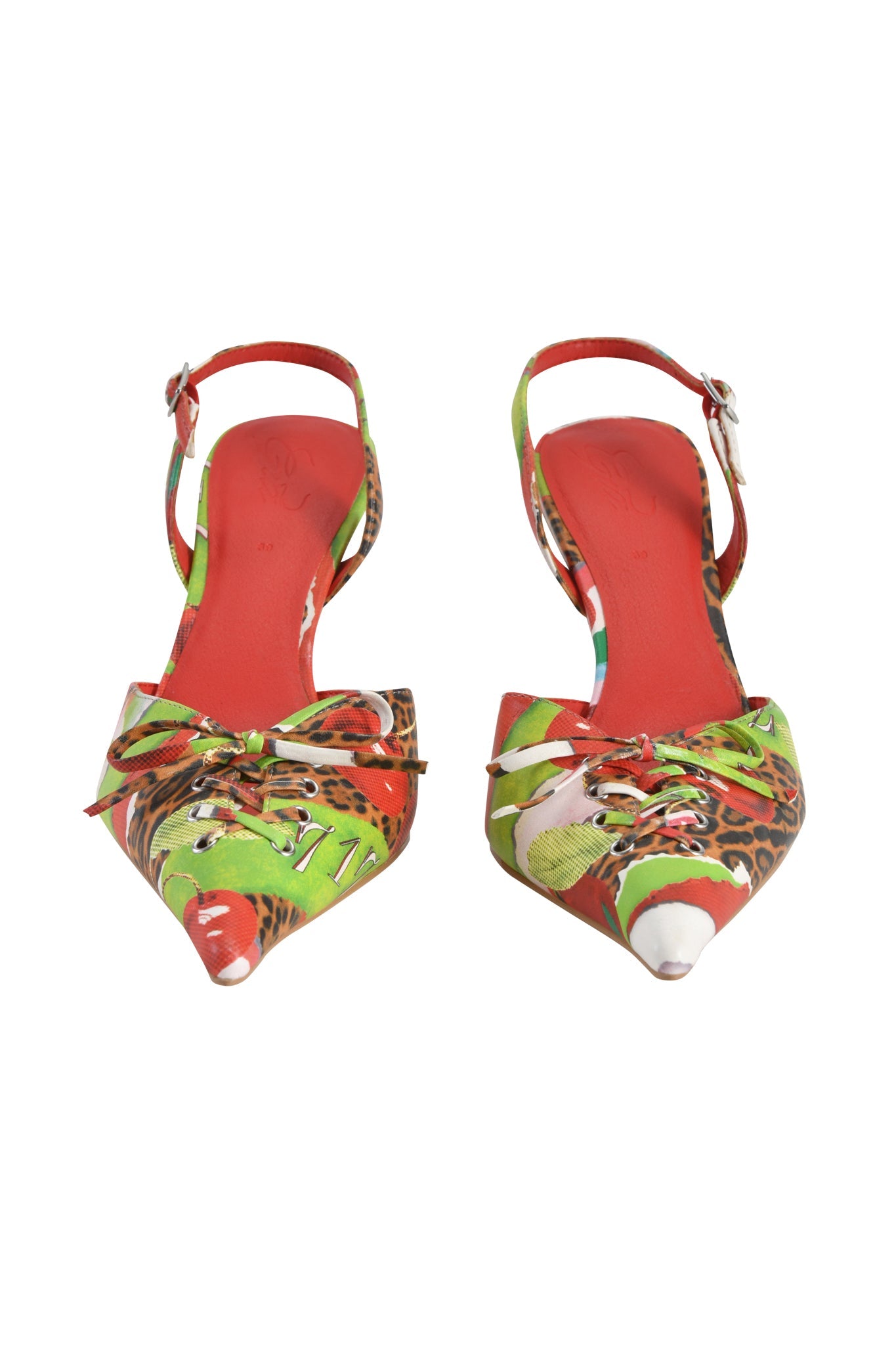 The NOORI MULE - WILD CHERRY by I.AM.GIA is a pointed-toe high heel with a vibrant red, green, and animal print, featuring front lace-up detail and ankle straps with buckles.