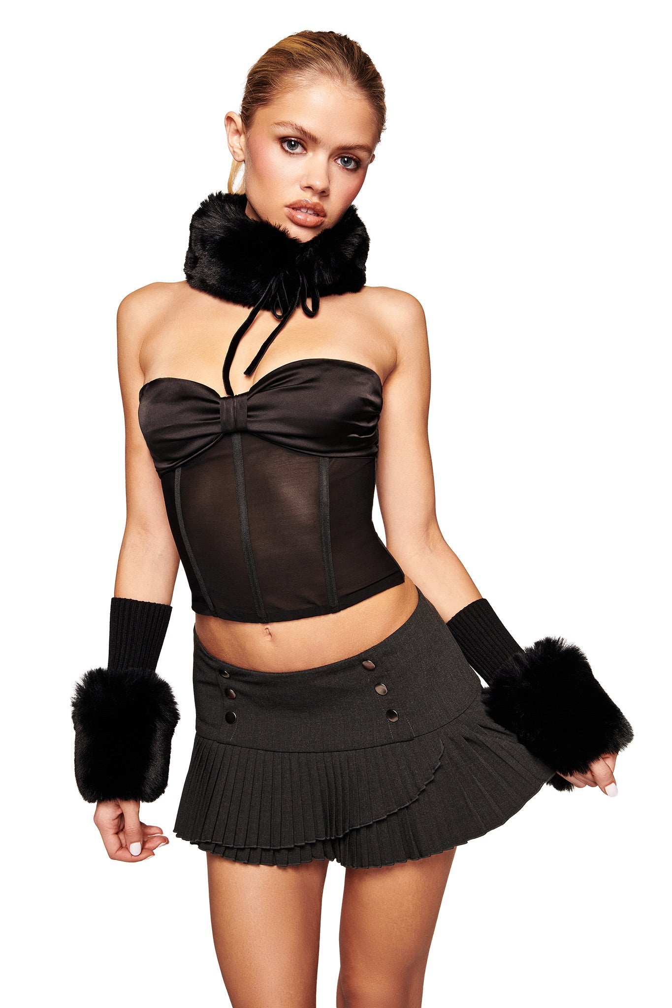 A woman poses against a white background wearing I.AM.GIA’s DENALI FUR RIB CUFF in black, styled with a strapless corset top, short pleated skirt, and a matching black furry choker.