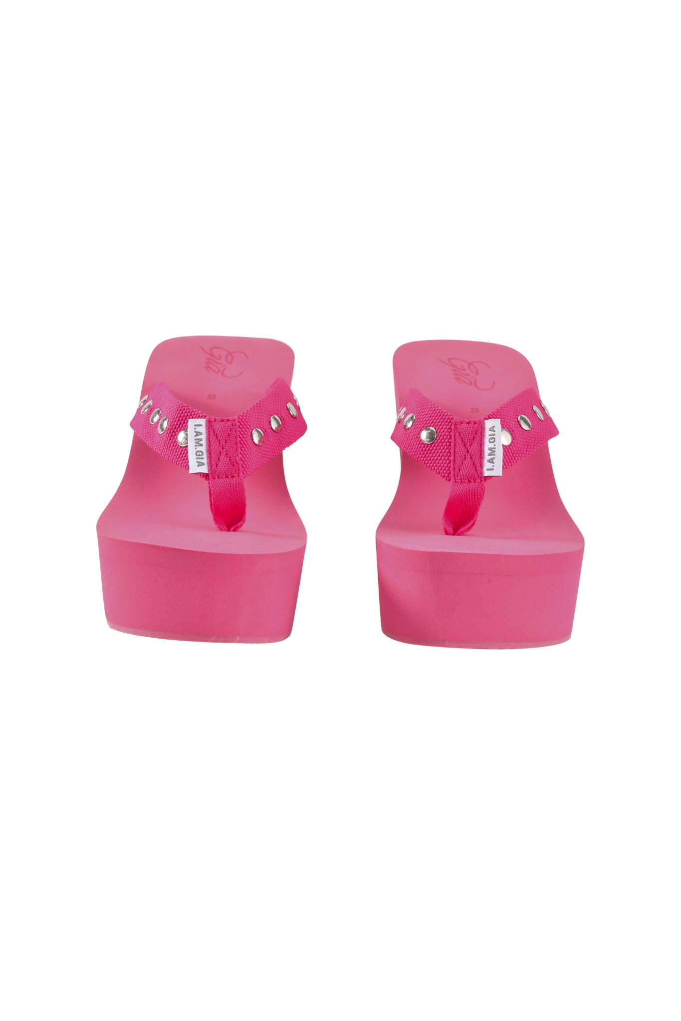 A pair of I.AM.GIA SHELBY STUDDED FLIP FLOP 2.0 sandals in hot pink, featuring studded straps and small white labels, shown from the front on a white background.