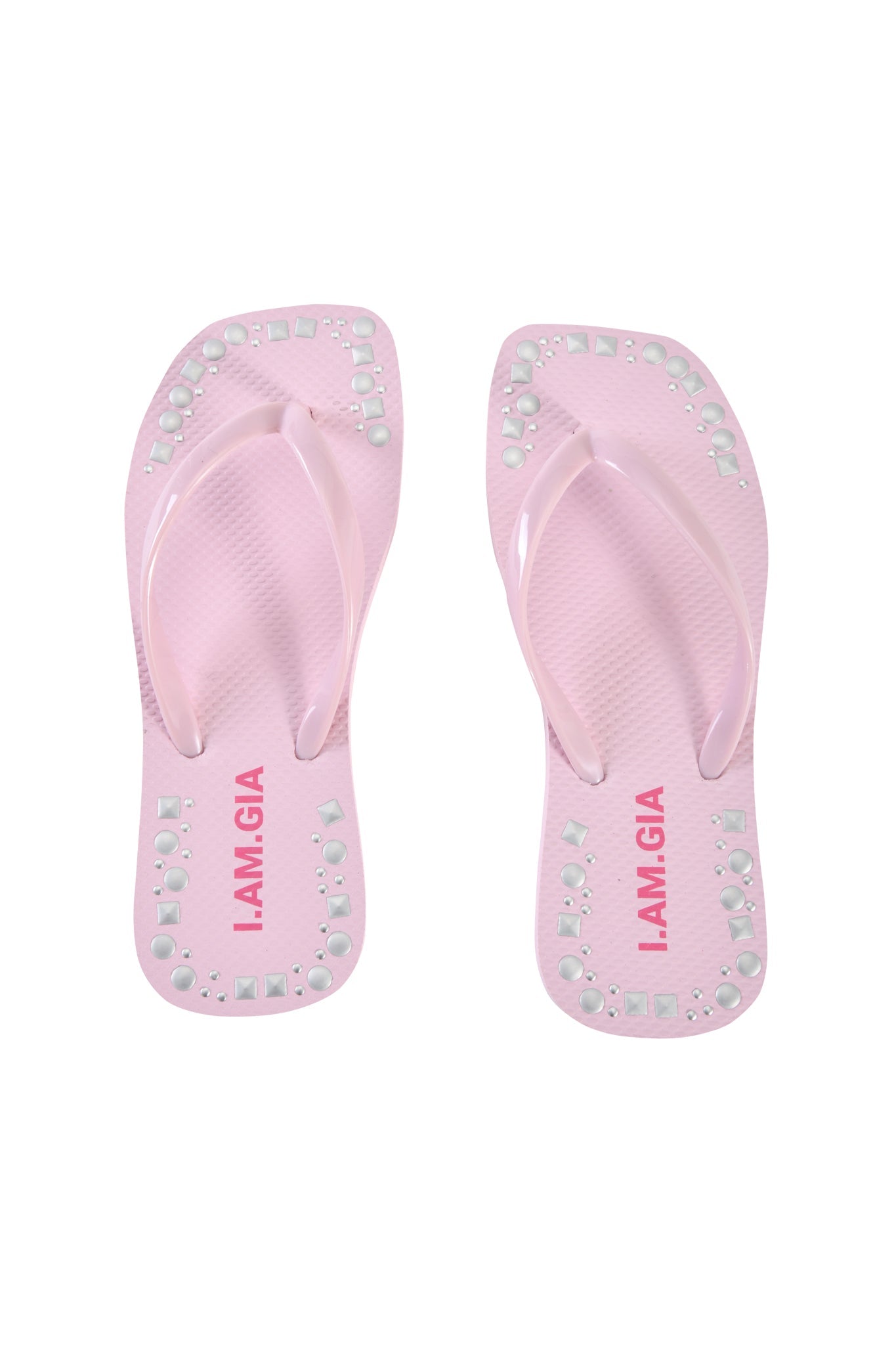 The INKA STUDDED FLIP FLOP in baby pink by I.AM.GIA features square toes, silver studs along the edges, and "I.AM.GIA" printed in pink on the footbeds.
