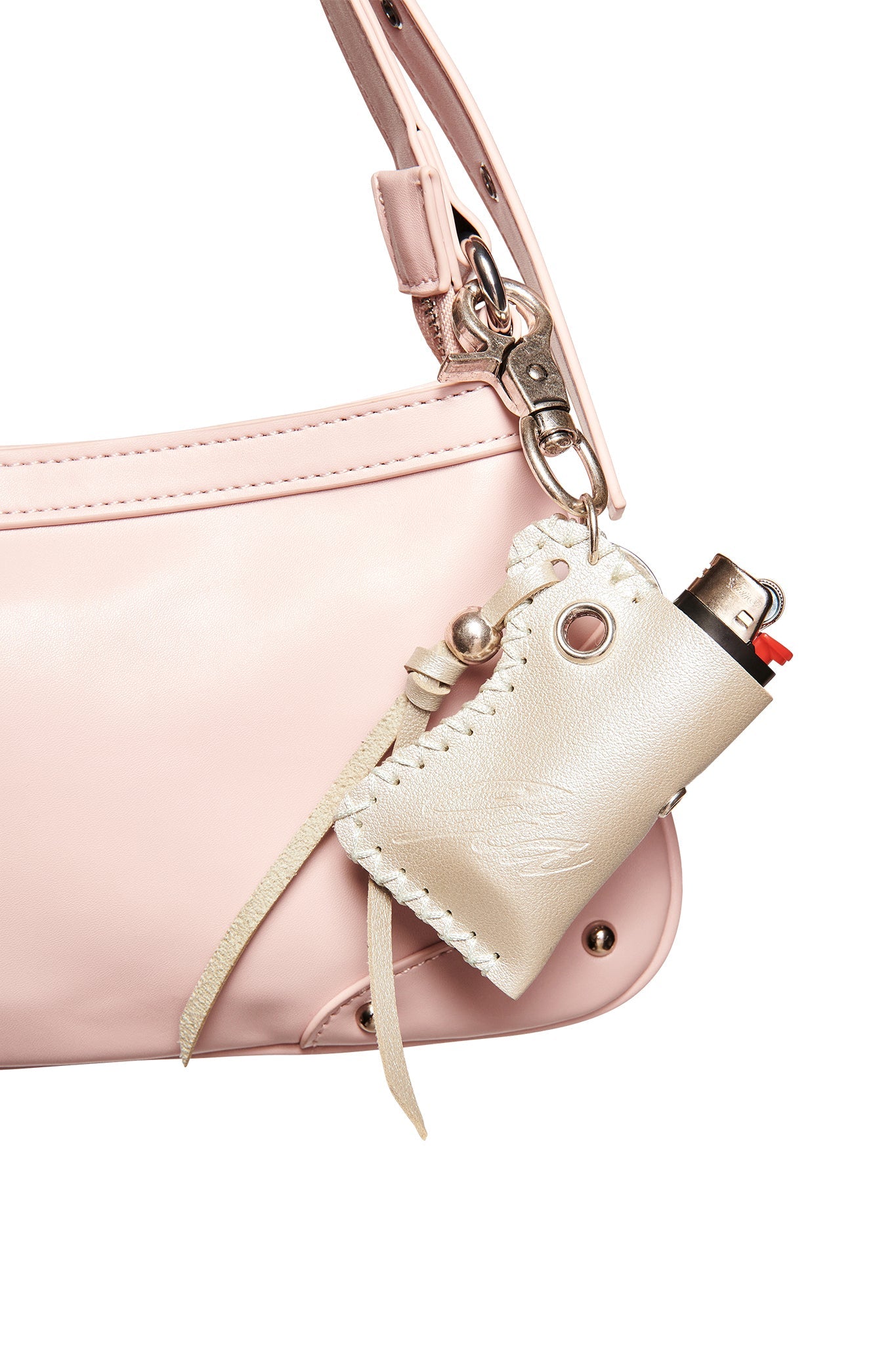 A close-up of a pale pink faux leather handbag features the I.AM.GIA VENUS LIGHTER KEYCHAIN in silver attached to the strap, holding a small black and red lighter.