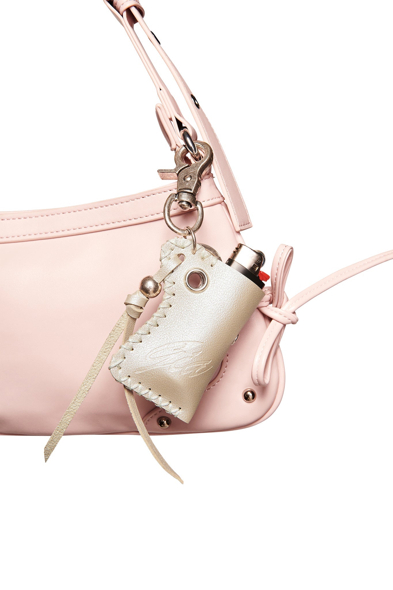 A close-up of a light pink faux leather handbag with a beige pouch attached, holding the I.AM.GIA VENUS LIGHTER KEYCHAIN in silver. The bag has a strap and metal hardware.