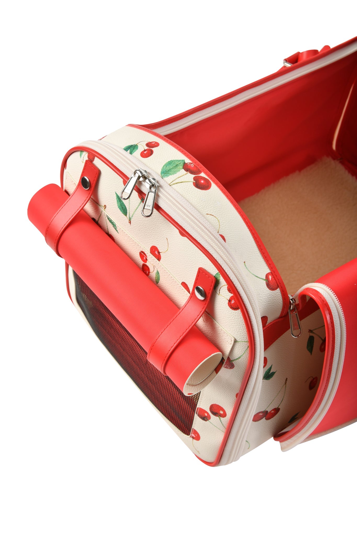 The TRIXX PET CARRIER - CHERRY ON TOP by I.AM.GIA is a small cream and red pet carrier with a cherry print, mesh ventilation window, rolled-up side flap, zippered openings, and an inner soft fleece pad.