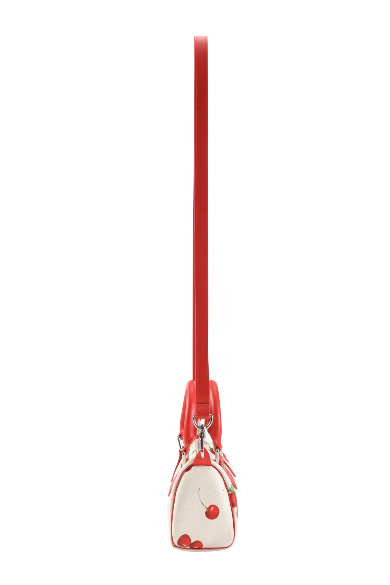 Side view of the I.AM.GIA NIKA MINI BAG - CHERRY ON TOP, featuring red trim, a long removable shoulder strap, and a cherry pattern near the bottom.