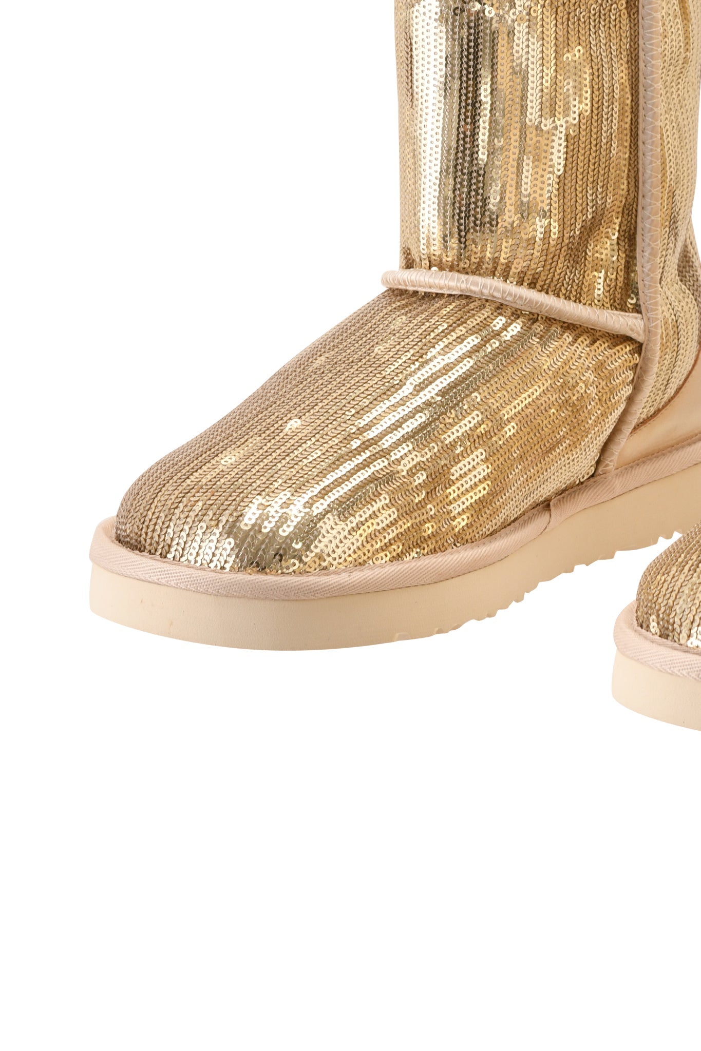 A close-up of the I.AM.GIA ELVIRA SEQUIN BOOT - GOLD highlights its shimmering gold sequin exterior, beige sole, and plush faux fur lining, capturing the striking texture and mid-calf silhouette.
