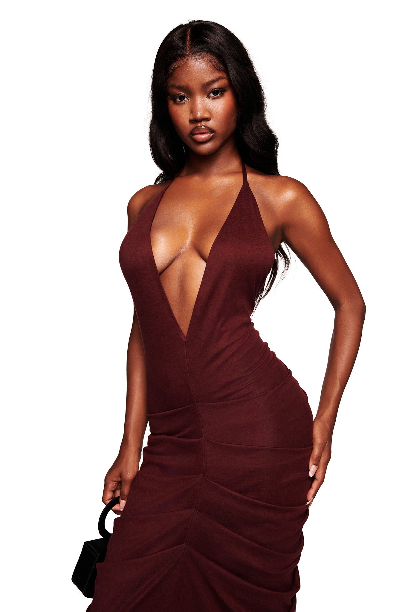 A woman poses confidently against a plain white background, wearing the I.AM.GIA US SASHI MAXI DRESS in plum and holding a small black handbag.