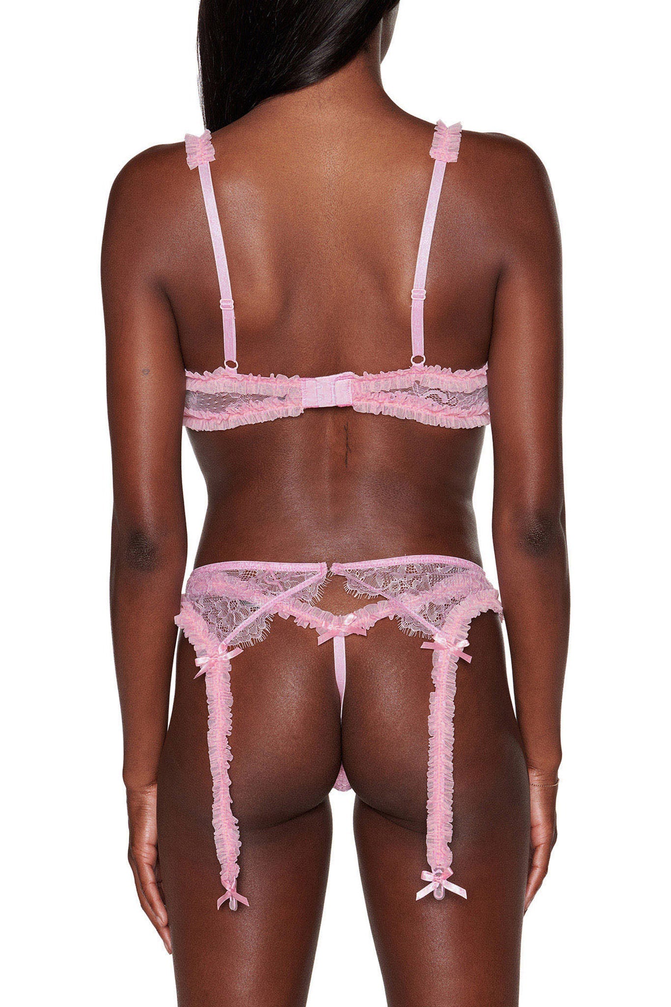 In the image, someone is wearing the MADISON 3 PIECE SET - PINK from I.AM.GIA, which includes an adjustable bra, garter belt, and lace thong. The back view highlights the intricate lace design and small bows on the straps set against a plain white background.