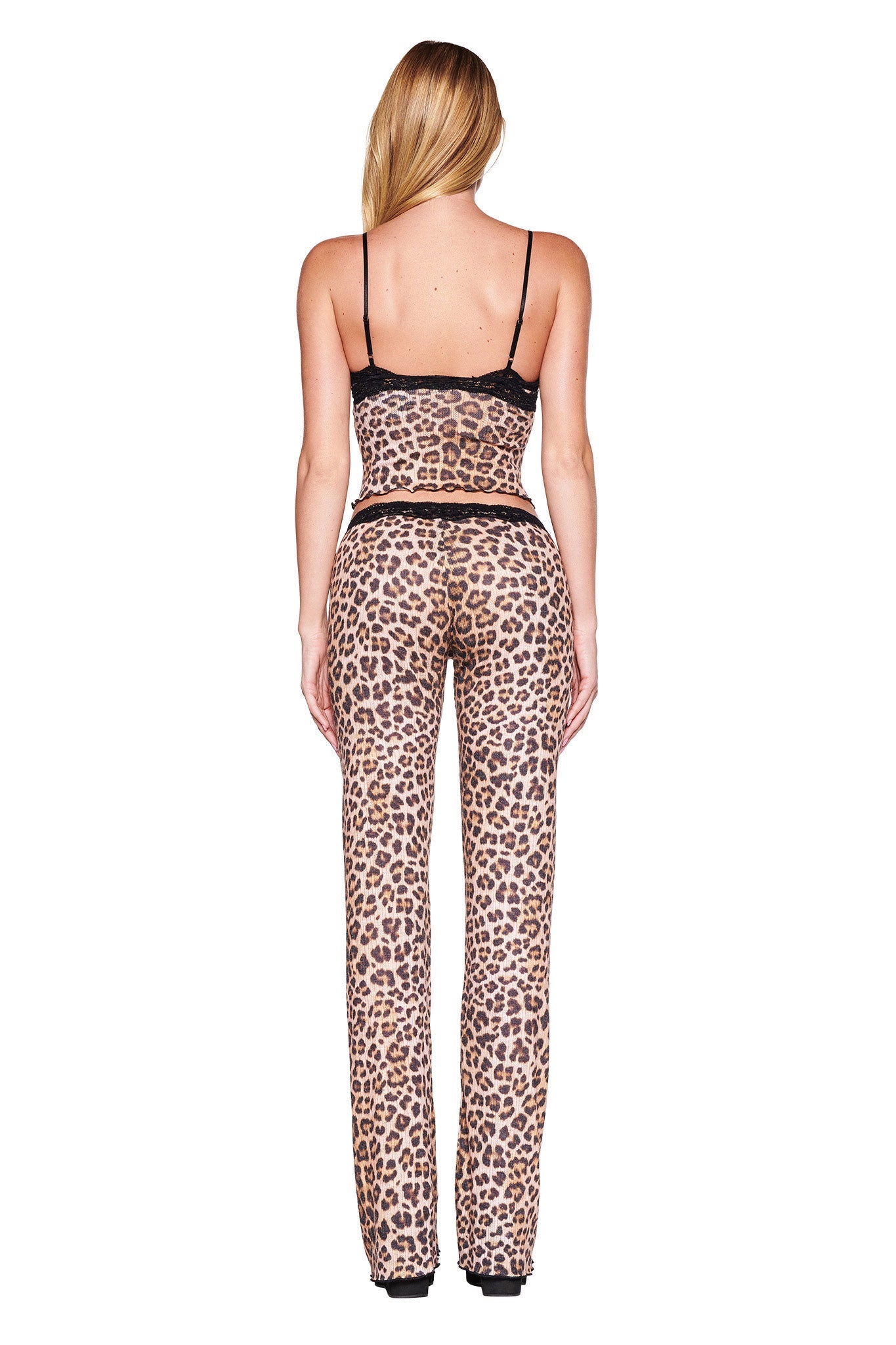 A woman is shown from behind wearing a custom leopard print matching set from I.AM.GIA, featuring the CASSIA TOP - NEUTRAL : LEOPARD, a sleeveless crop top with lace trim paired with high-waisted pants. She has long blonde hair and poses against a white background.