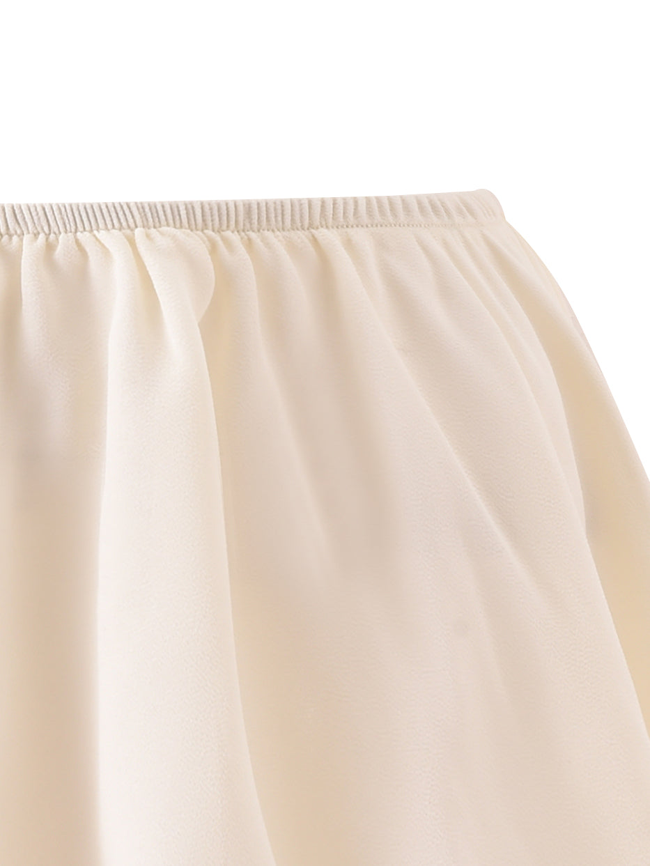 Close-up of an off-white, gathered, chiffon-like skirt featuring an elastic waistband and soft, flowing fabric—a flouncy mini skirt from I.AM.GIA’s OCEANA CORSET SET in brown, perfect for pairing with a vintage-washed bustier or adding a whimsical touch to a sexy pirate costume.
