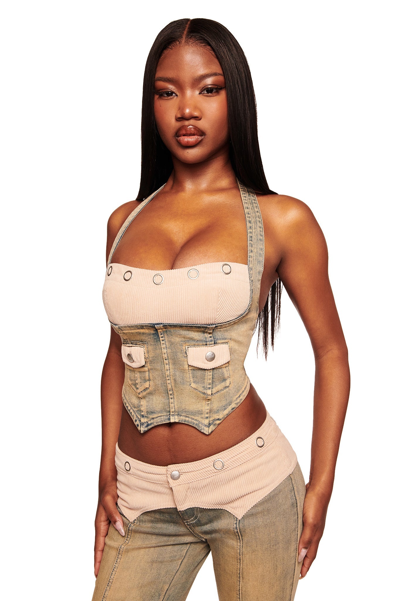A woman with long straight hair wears the I.AM.GIA TOMMIE CORSET in antique denim with matching low-rise pants, both featuring button and pocket details, standing against a white background.