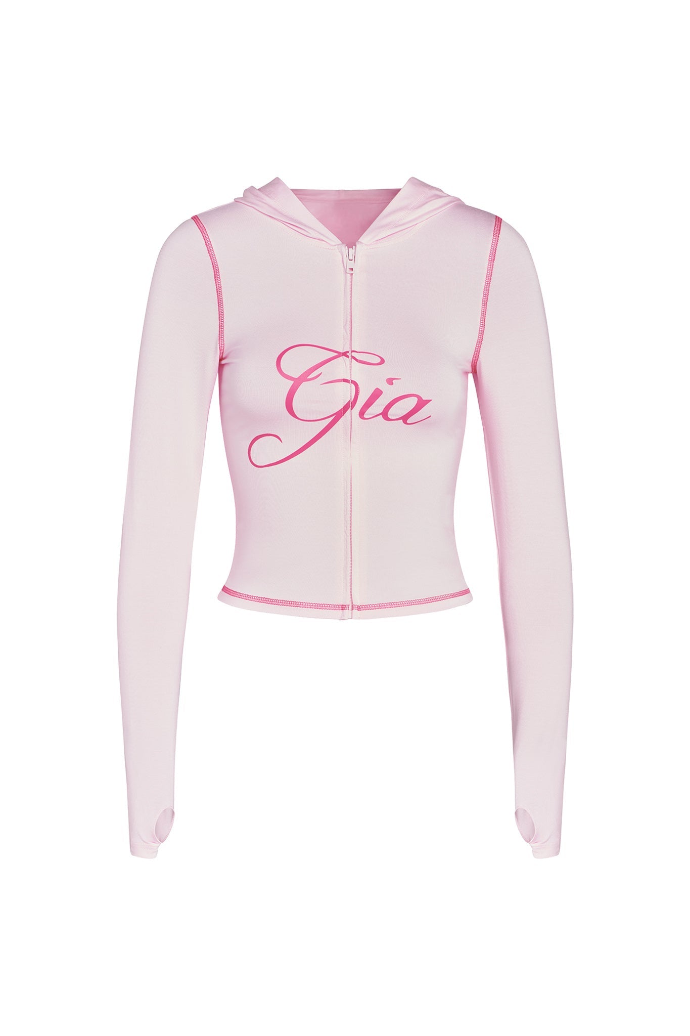 The BLARE HOODIE in pastel pink by I.AM.GIA is a light pink cropped hoodie featuring long sleeves with thumb holes at the cuffs. It showcases the name "Gia" written in bold, cursive dark pink letters across the chest and has a zipper that runs from the hood to the hem.