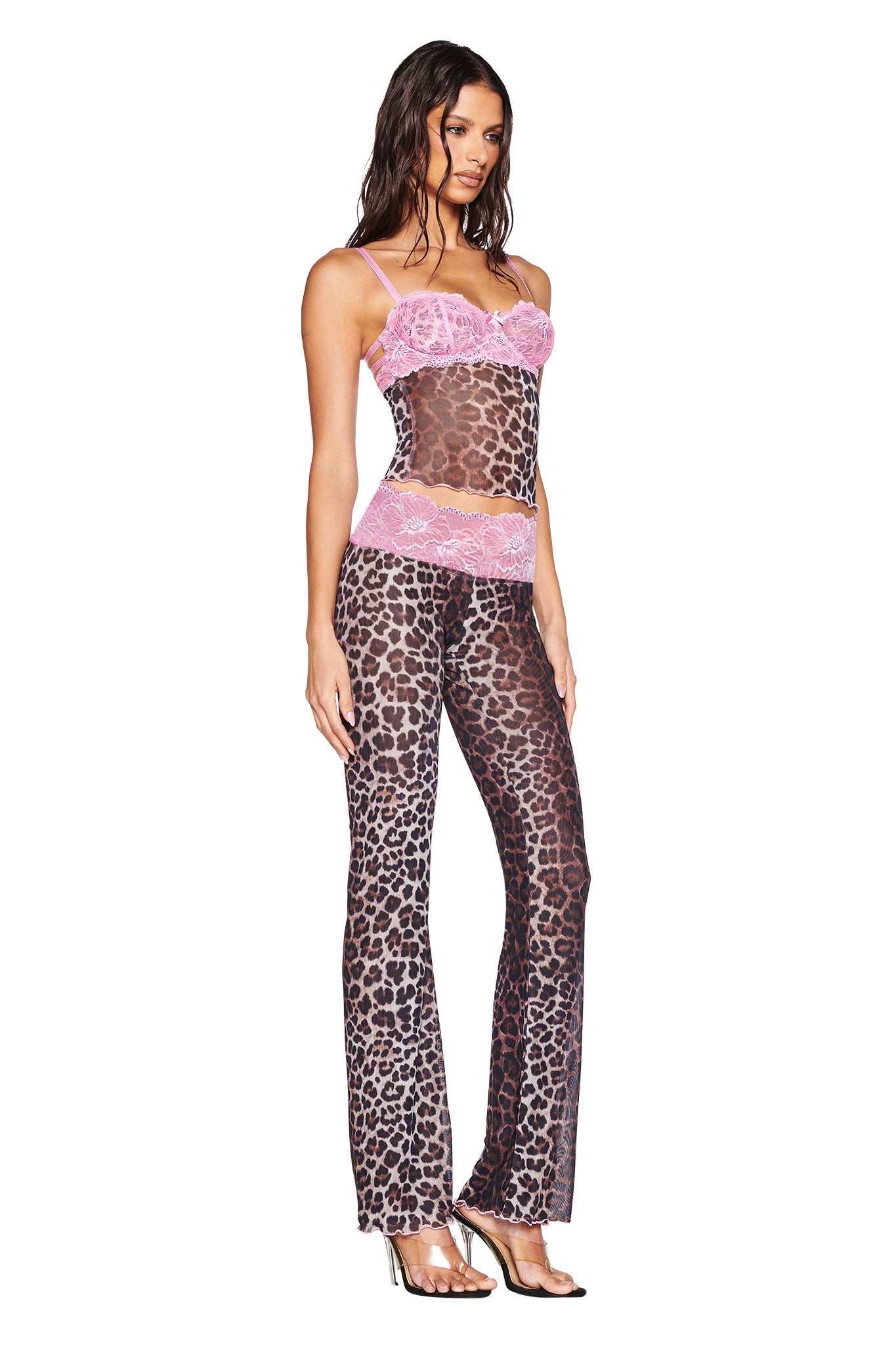 A woman models I.AM.GIA’s SILO PANT in classic leopard print with a matching sheer camisole featuring pink lace trim, paired with silver high-heeled sandals against a white background.