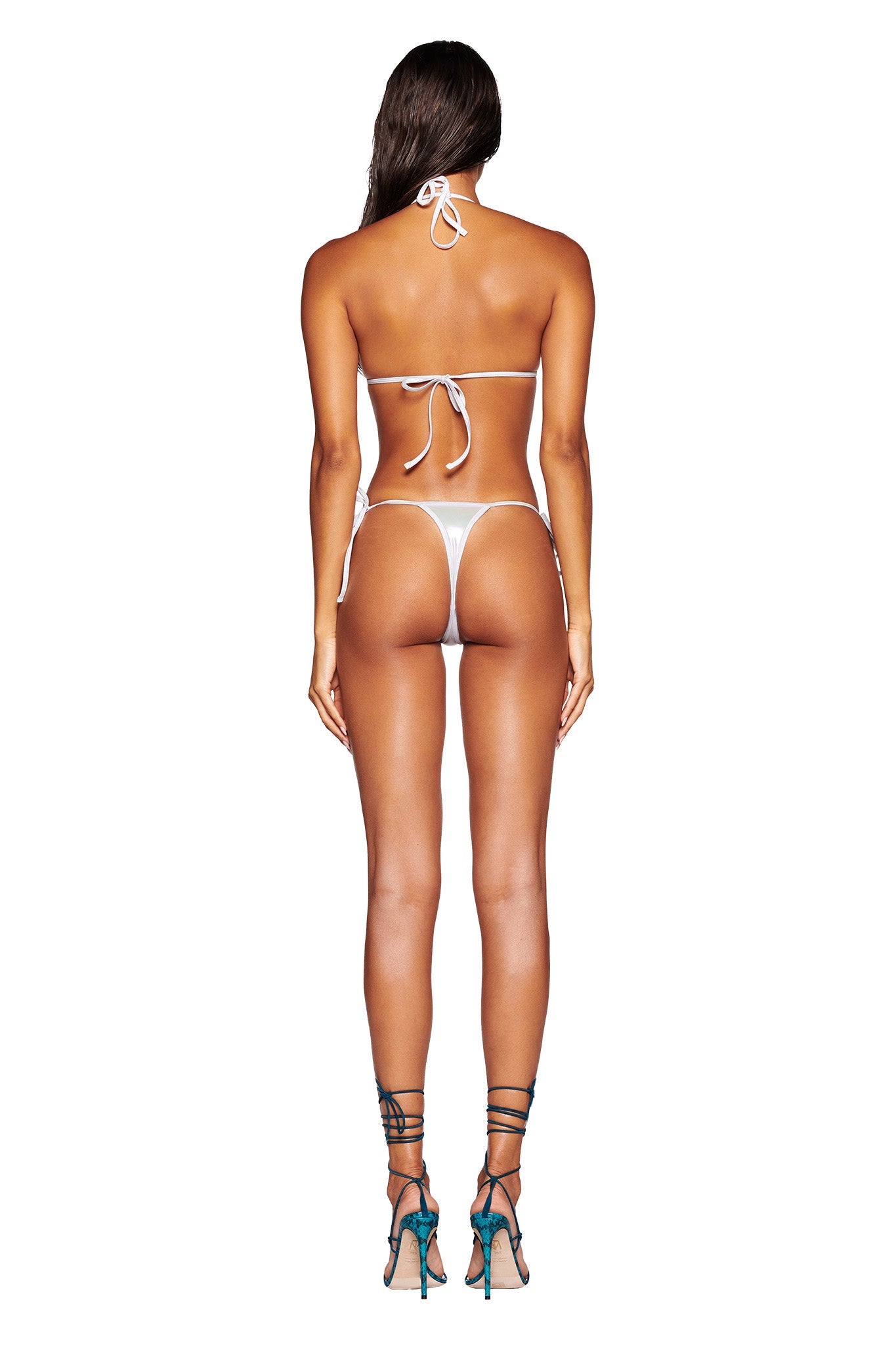 A woman stands with her back to the camera, wearing an I.AM.GIA ALOHI BIKINI TOP in white pearl and high-heeled shoes. The bikini top features ties at the neck and back, showcasing her entire body from head to toe against a plain white background.