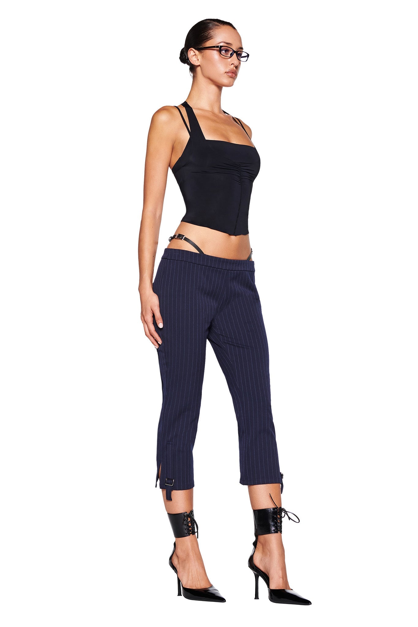 Close-up of the lower part of the MARRION CAPRI - BLUE : PINSTRIPE by I.AM.GIA, showcasing fine vertical stripes. These navy capris feature a strap with a small silver buckle near the bottom hem of each leg, enhancing the adjustable side straps and straight leg silhouette.