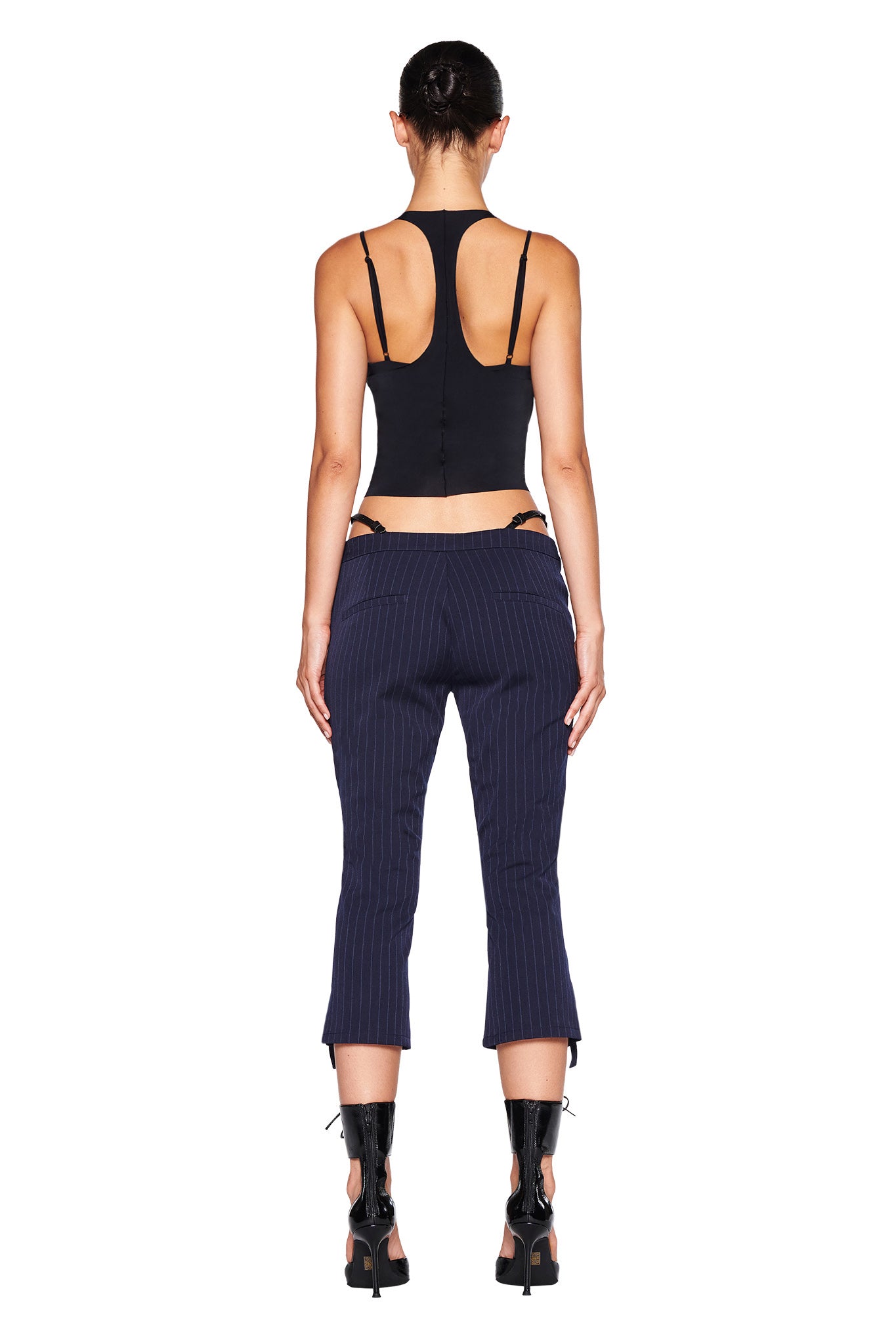 Close-up of the lower part of the MARRION CAPRI - BLUE : PINSTRIPE by I.AM.GIA, showcasing fine vertical stripes. These navy capris feature a strap with a small silver buckle near the bottom hem of each leg, enhancing the adjustable side straps and straight leg silhouette.