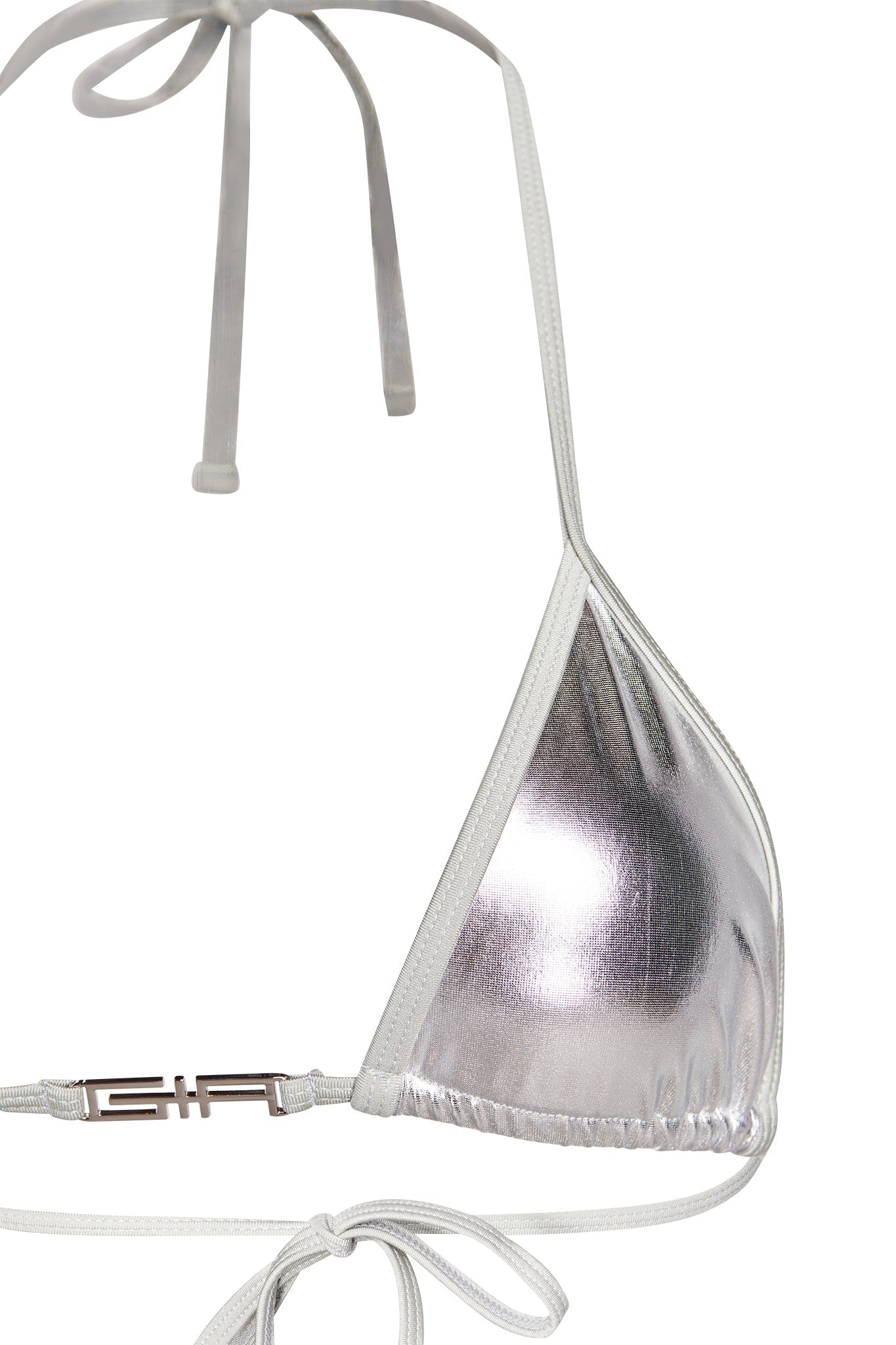A close-up of the ALOHI BIKINI TOP - GREY : SILVER from I.AM.GIA. The top showcases a halter neck tie and a back tie, with its shiny, reflective fabric catching the light perfectly. The bottom band is adorned with a small metallic clasp, which features branding engraved on the left side.
