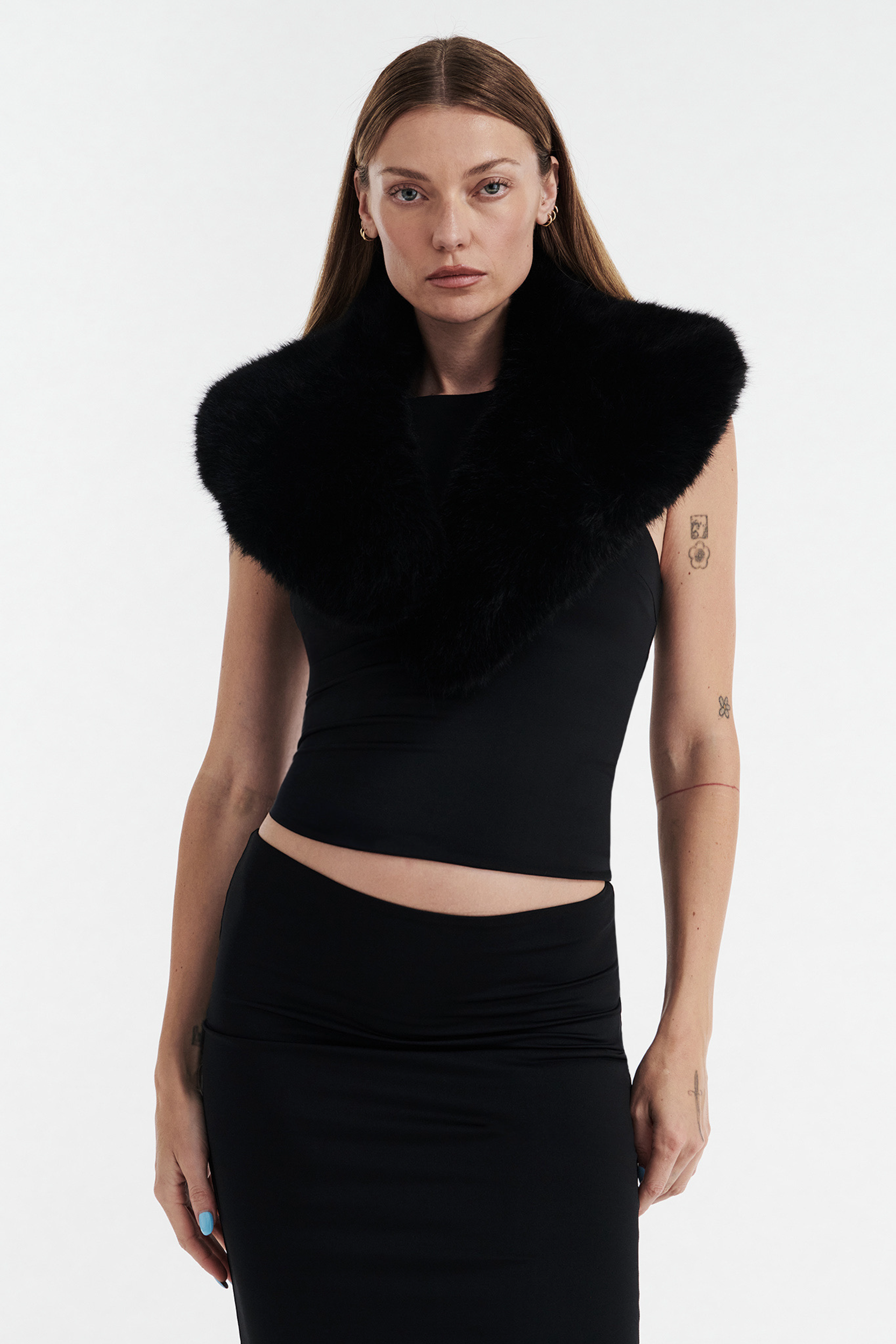 A woman with long straight hair models the CDP SHIRLEY FAUX FUR COLLAR in black over a sleeveless black crop top and skirt, standing against a plain white background and looking directly at the camera.