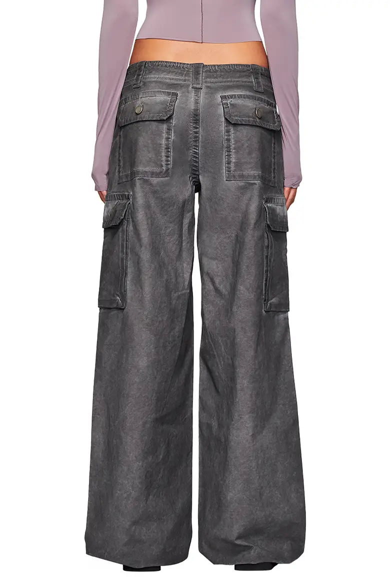 A person is seen from behind wearing I.AM.GIA’s JAXXON CARGO PANT in washed black with oversized wide legs and flap pockets, paired with a long-sleeve light mauve top.