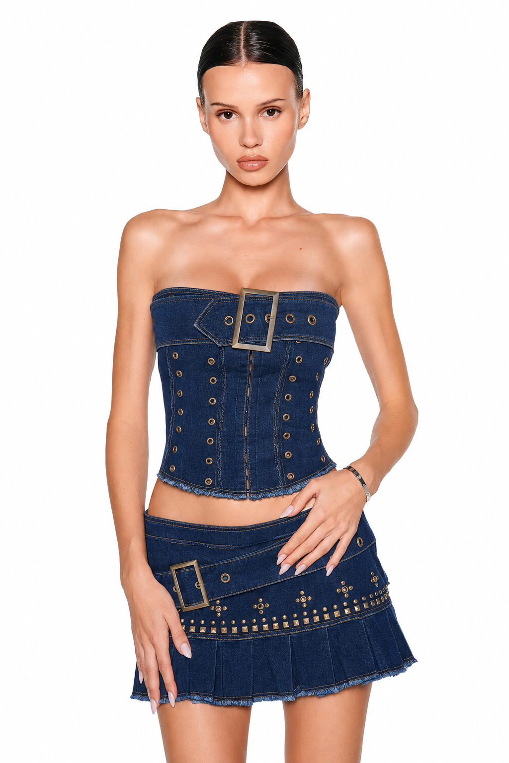 A woman models the I.AM.GIA MASON CORSET in dark denim, styled with a matching mini skirt featuring gold studs and a decorative buckle, posing against a white background.