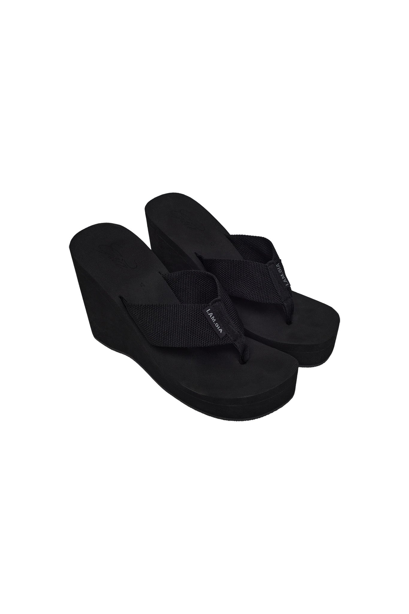 The SHELBY FLIP FLOP - BLACK from I.AM.GIA is displayed against a white background, showcasing its black fabric straps and slightly elevated wedge heel for a casual yet stylish look. These flip-flops bring a touch of trendsetting sophistication to your summer wardrobe.