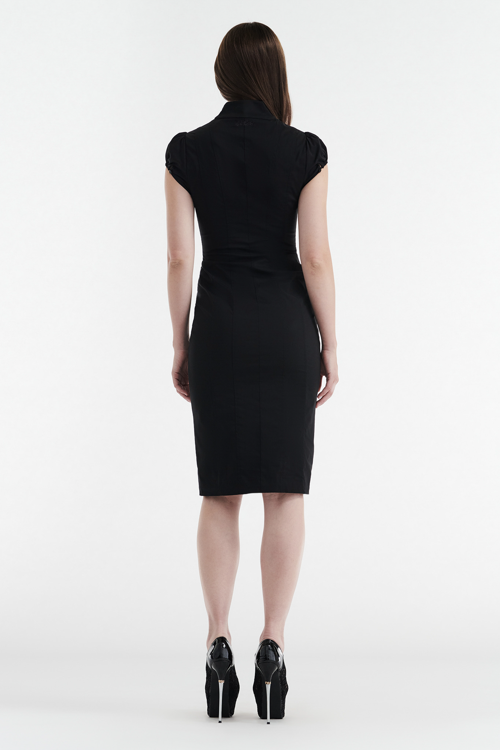 A woman with straight brown hair wears the CDP COLETTE Panelled Puff Sleeve Midi Dress in black, paired with black high-heeled shoes, as she stands facing away against a plain white background.