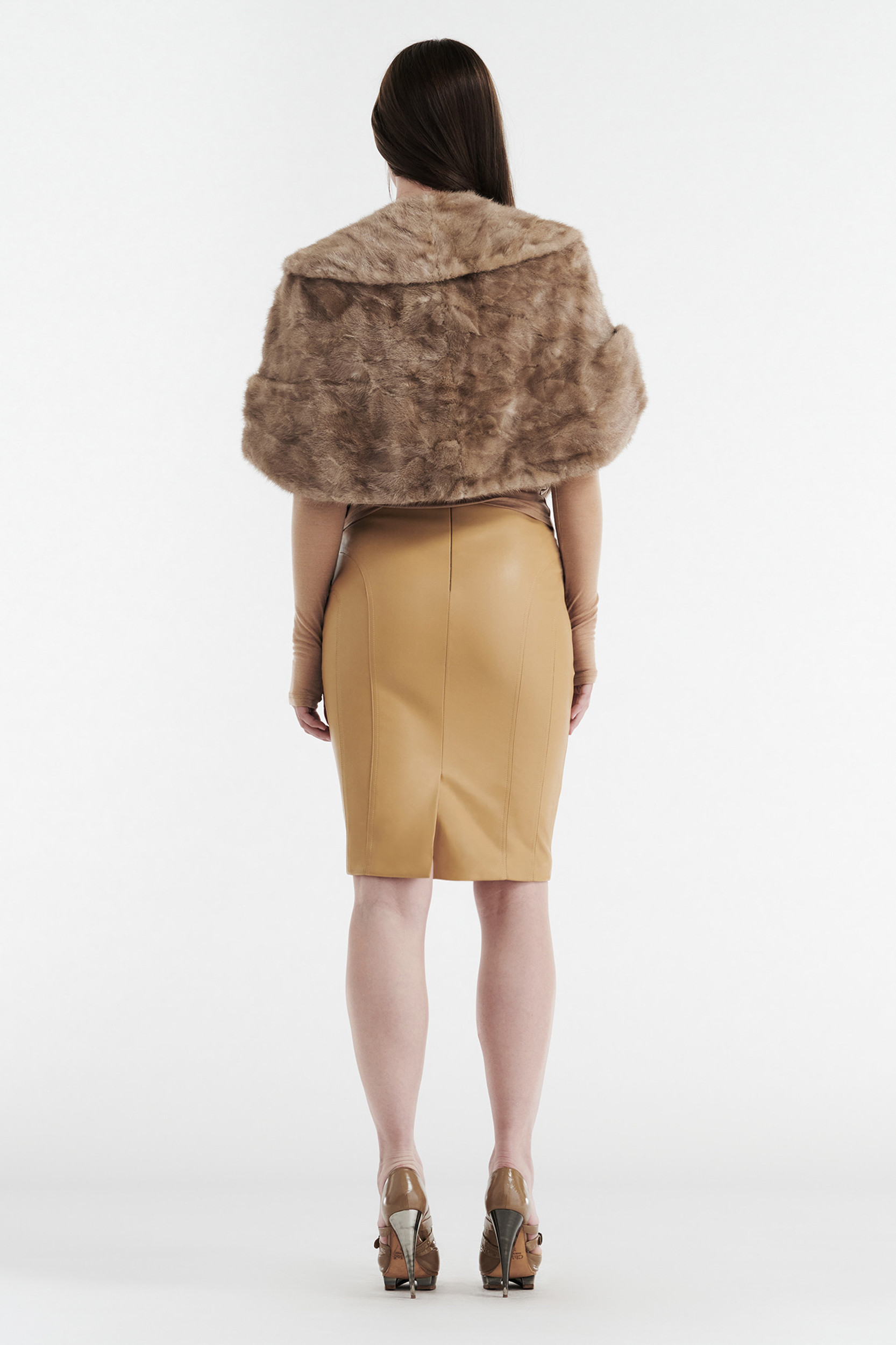A woman faces away, wearing the CDP INES Faux Leather Pencil Skirt in tan with a brown faux fur stole, tan gloves, and high heels against a plain white background.