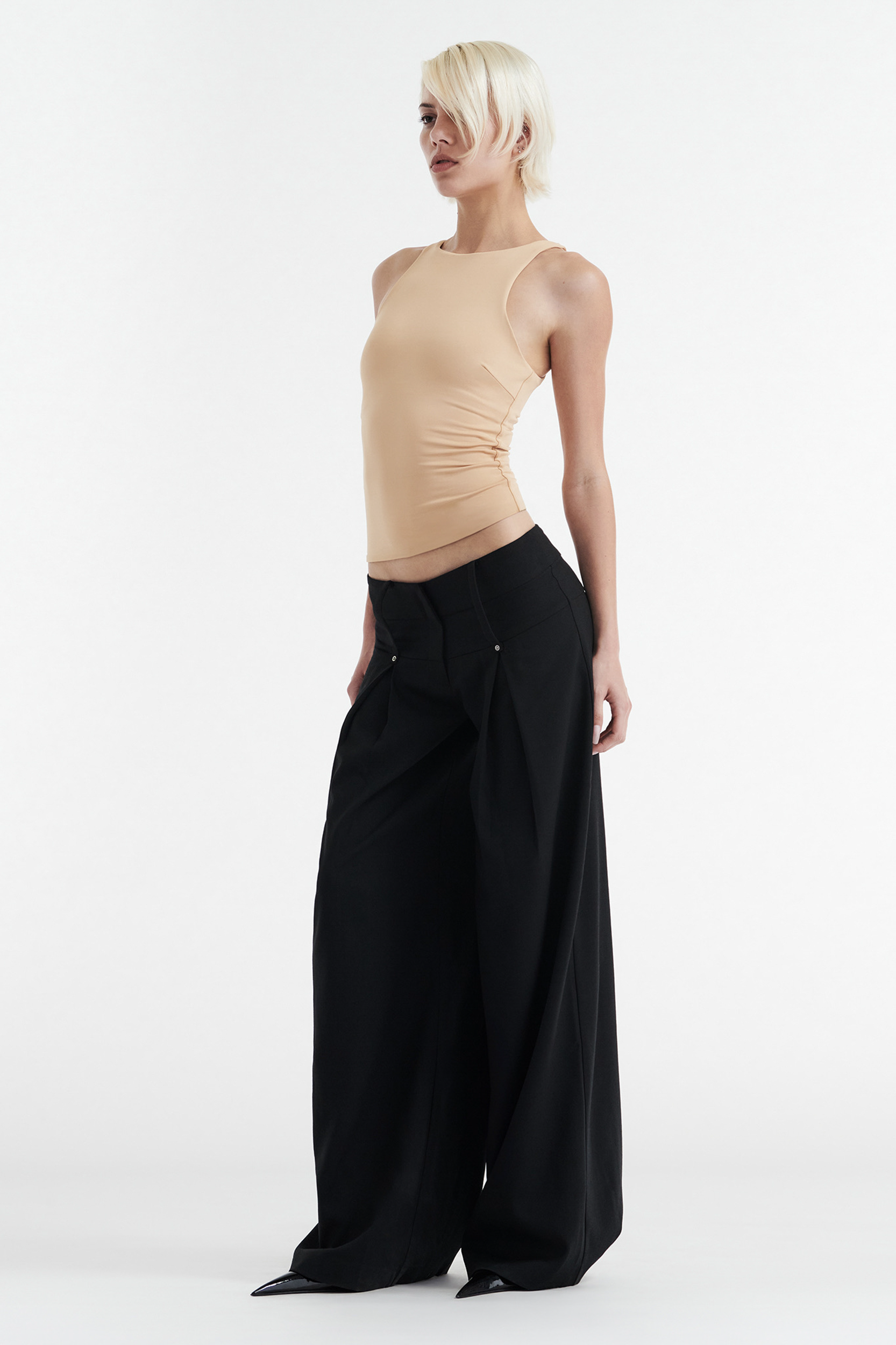 A person with short blond hair wears the CDP SOPHIE BASIC SLEEVELESS TANK WITH SHELF BRA in tan and high-waisted, wide-leg black pants, standing against a plain white background.