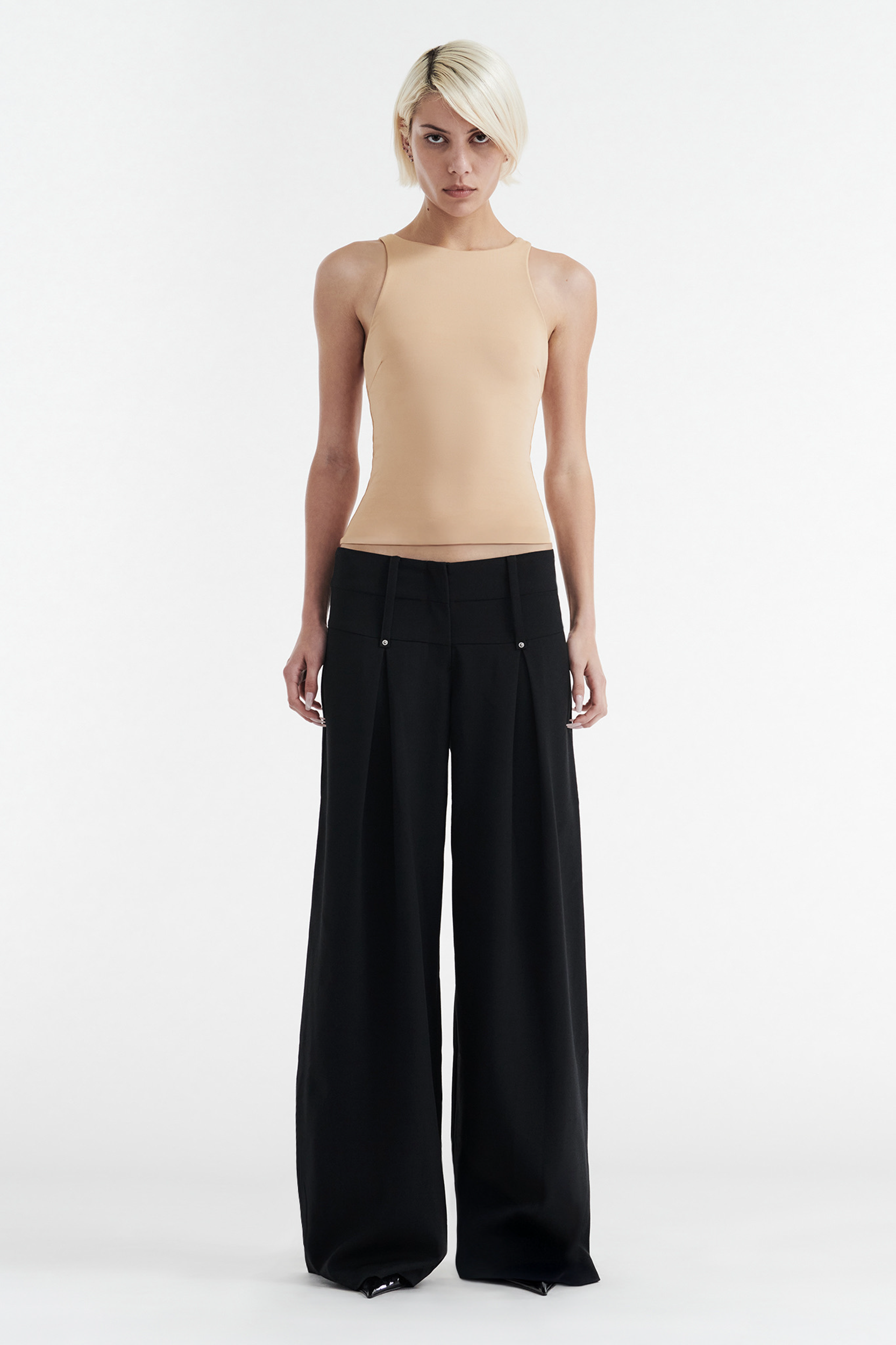 A person with short blonde hair wears a sleeveless beige top and the CDP CHARLOTTE WIDE LEG PLEAT PANT in black, standing against a plain white background.