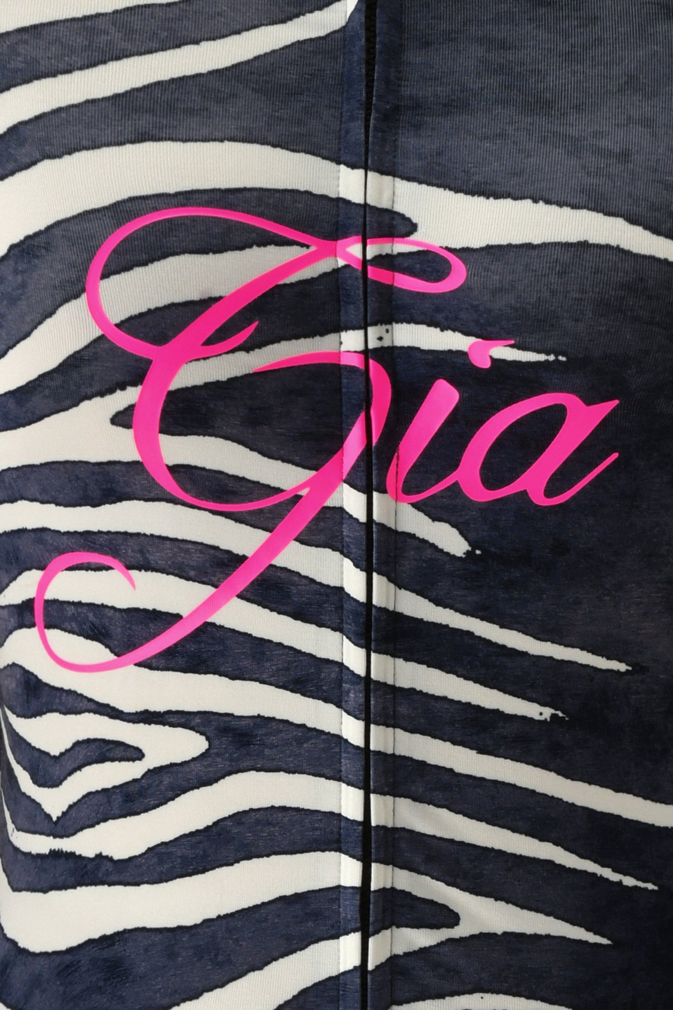 A close-up of black and white zebra print fabric, evoking the striking I.AM.GIA BLARE HOODIE - BLACK WILD SIDE, with the word “Gia” displayed in bold, pink cursive across the center.