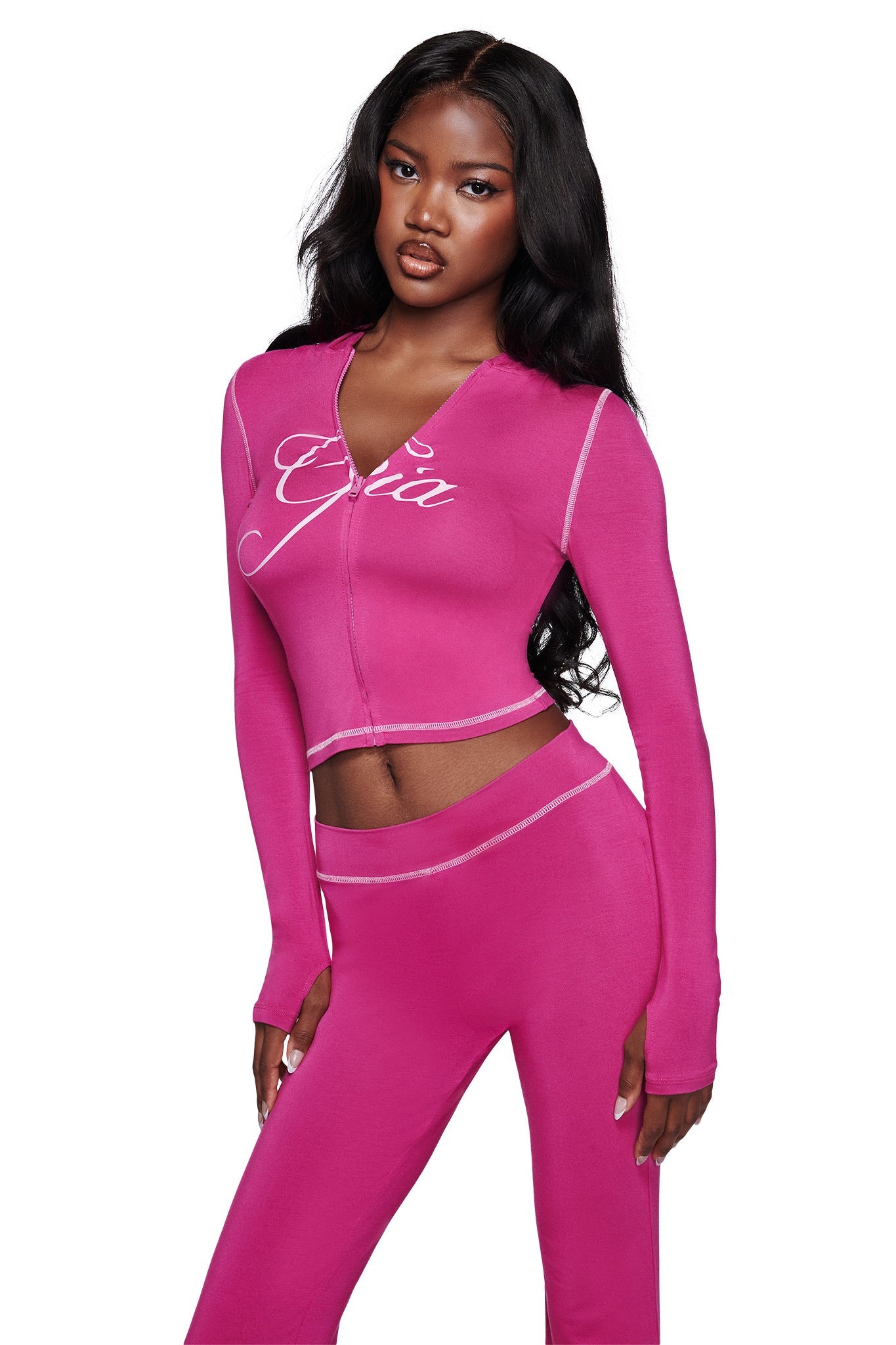 A woman with long, wavy black hair poses against a white background wearing the I.AM.GIA BLARE HOODIE in raspberry, a fitted two-piece featuring bold white stitching and signature branding for iconic style.