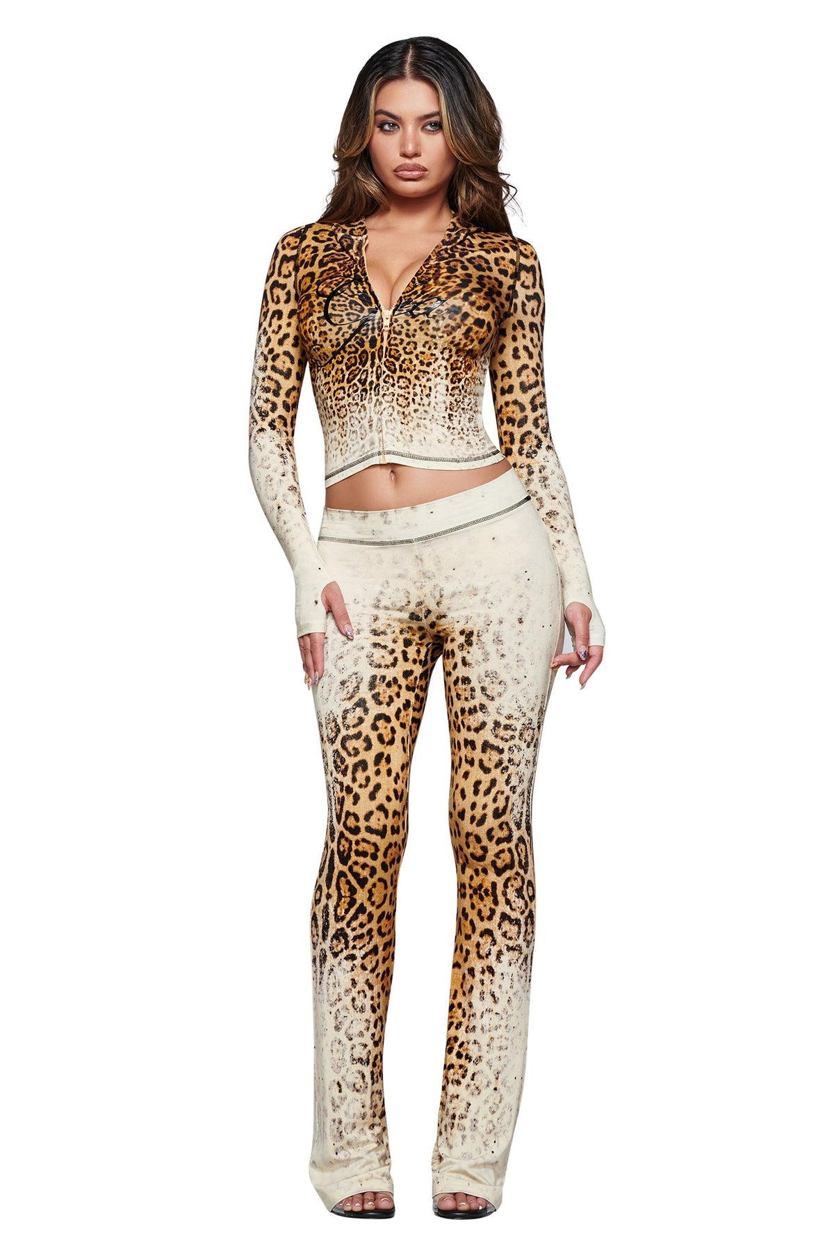 A woman stands against a white background wearing the I.AM.GIA BLARE HOODIE in Cream Faded Panthera—a matching long-sleeve zip-up top and pants set featuring a gradient panther print with a hoodie-inspired design.