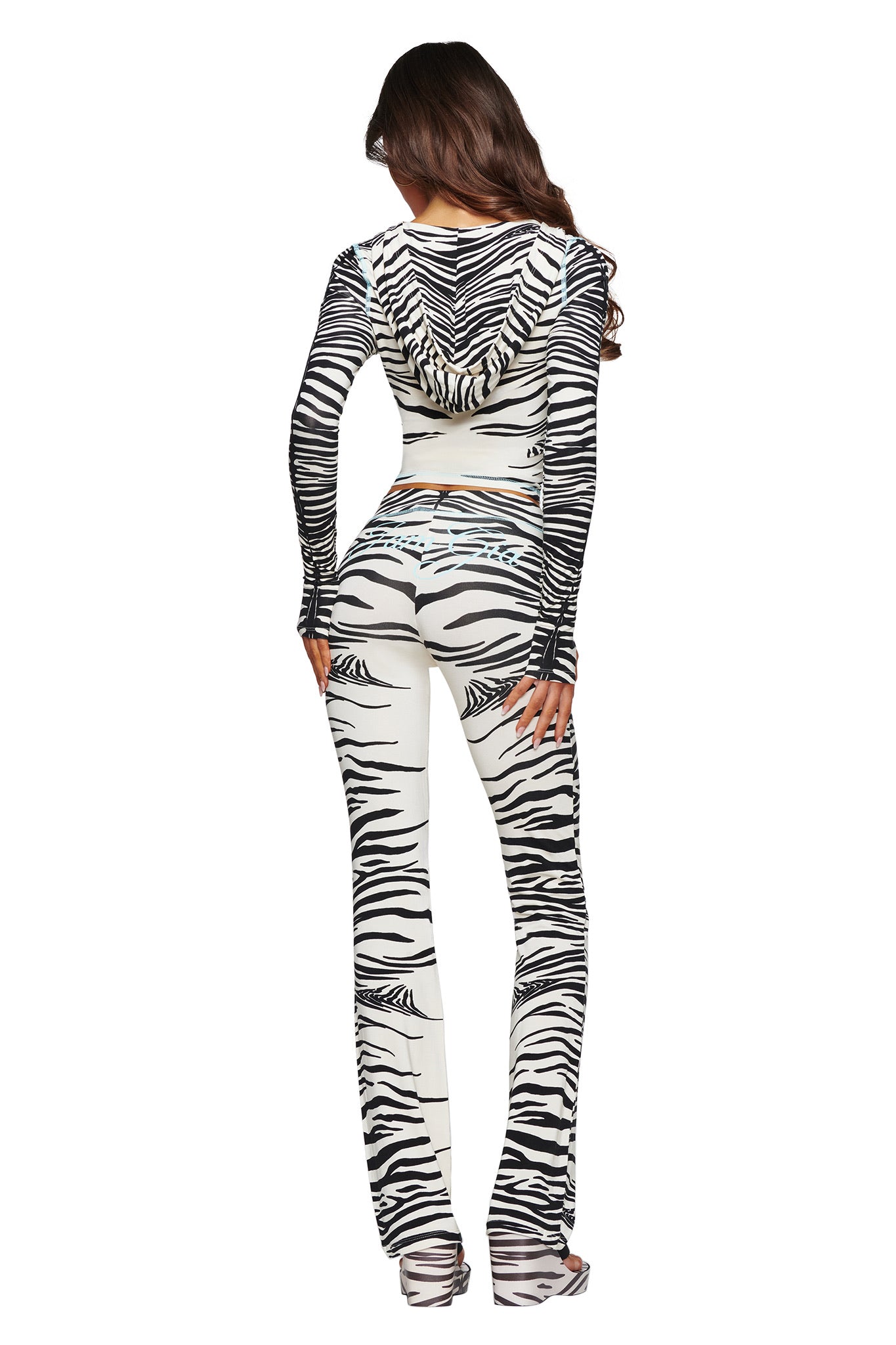 A woman stands with her back to the camera, wearing the I.AM.GIA BLARE HOODIE - FINE LINE ZEBRA and matching fitted pants, against a white background.