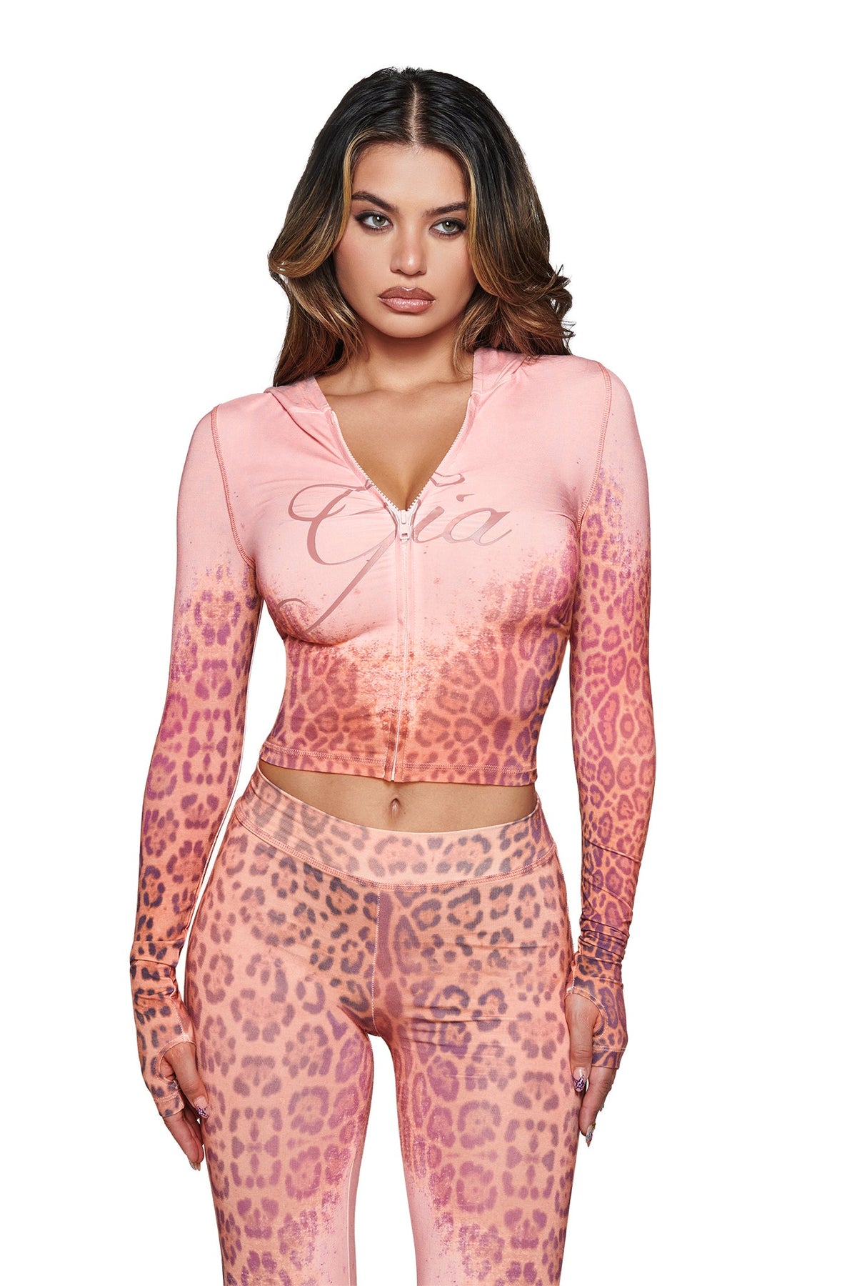A woman models the I.AM.GIA BLARE HOODIE in Pink Faded Panthera, paired with matching leggings, standing against a white background and looking directly at the camera with a neutral expression.