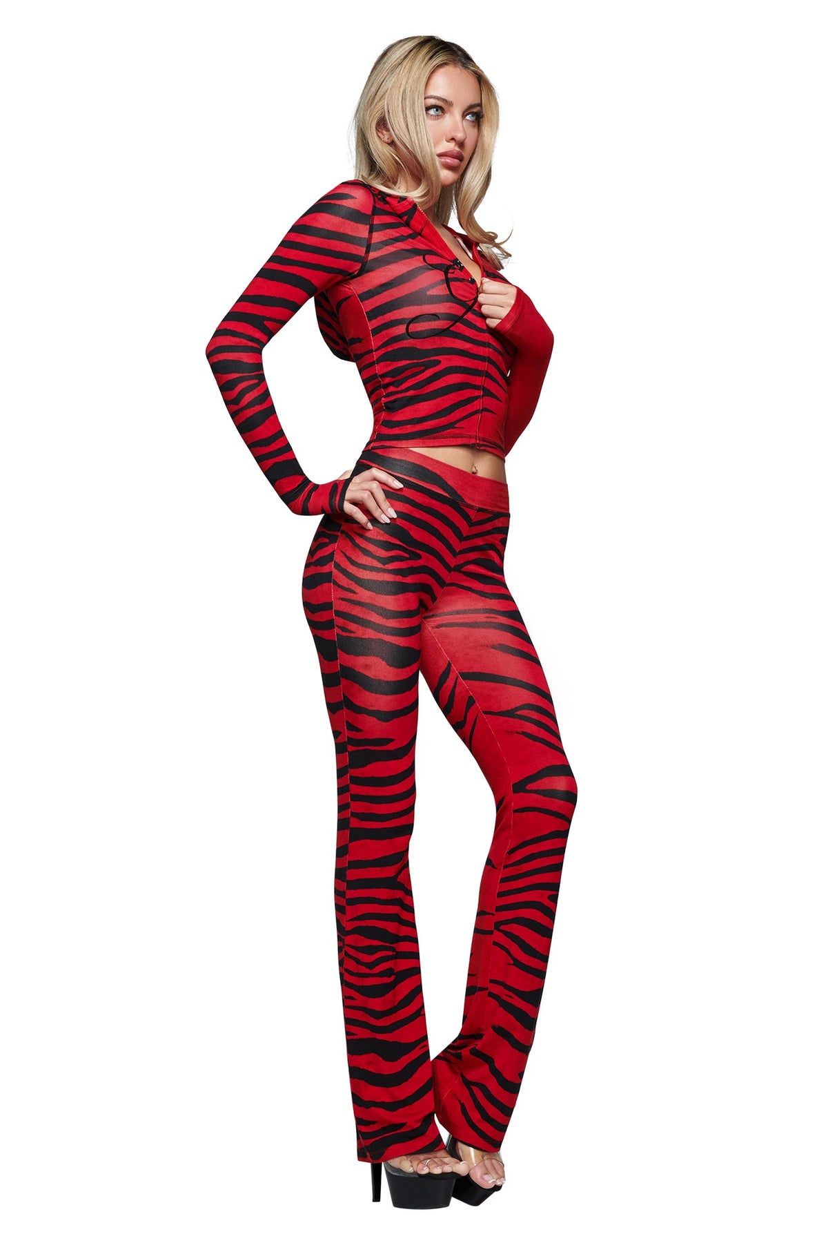 A woman wears the I.AM.GIA BLARE HOODIE in the Red Wild Side tiger-striped print, a long-sleeve crop top crafted from eco-friendly bamboo fabric, paired with matching flared pants and black high heels, standing against a white background.