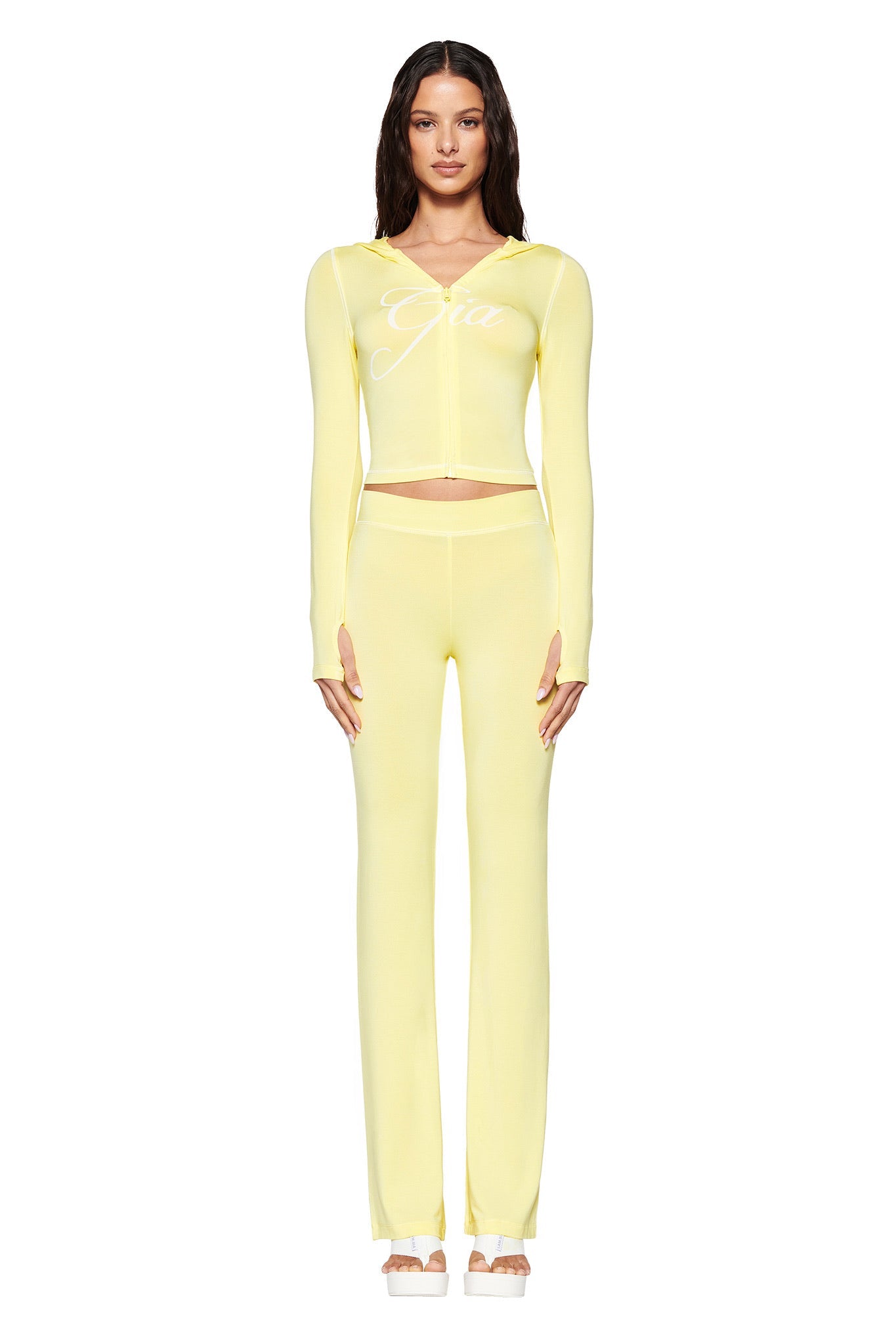 A person stands against a white background, wearing a pale yellow BLARE Hoodie by I.AM.GIA and matching sleek bodycon pants. They have long dark hair and are looking directly at the camera.