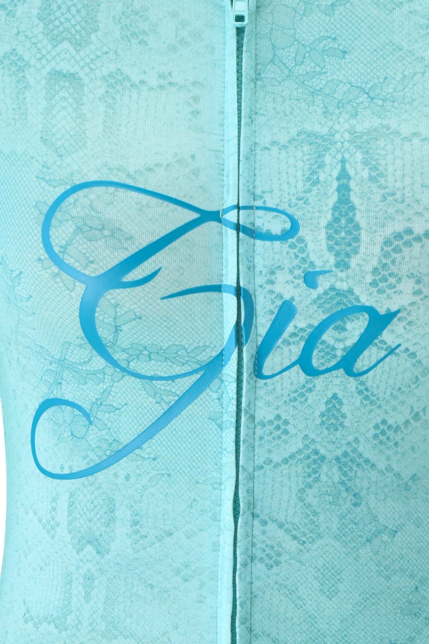 Close-up of teal, lace-patterned BLARE HOODIE - TEAL SERPENTINE by I.AM.GIA. "Gia" appears in elegant script across the center, with a visible vertical zipper adding a stylish touch to the design.