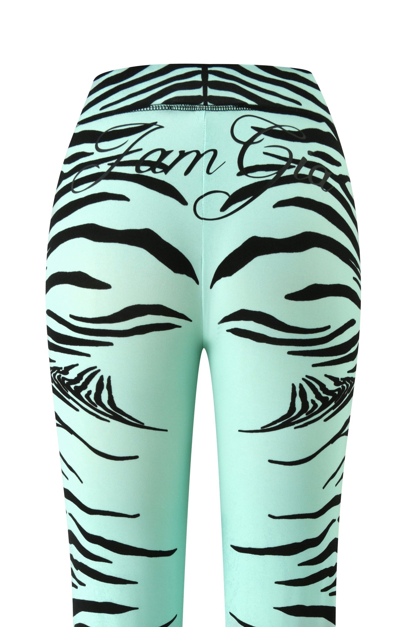 A close-up of the back of the BLARE TRACKPANT - AQUA FINE LINE ZEBRA by I.AM.GIA showcases mint green trackpants with black fine line zebra stripes and cursive “Glam Girl” text across the waistband, blending playful style with a modern flared silhouette.