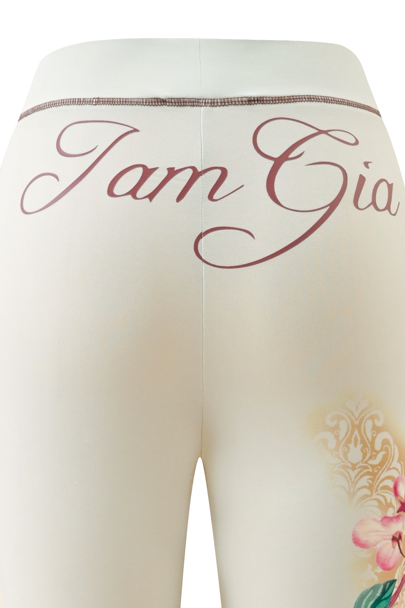 Close-up of the back of the cream-colored BLARE TRACKPANT - BLOSSOM by I.AM.GIA, featuring “I.AM.GIA” in cursive across the waistband and a delicate blossom-inspired floral print on one leg.