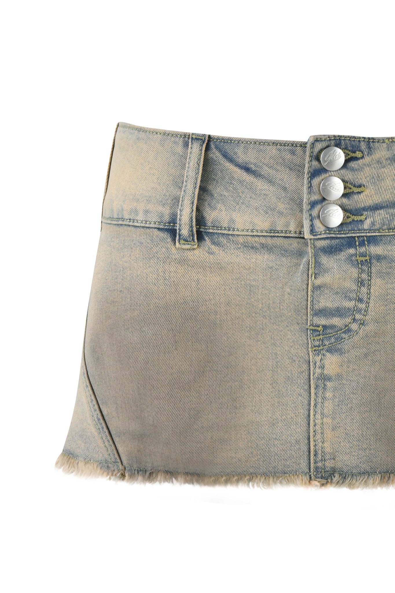 Close-up of an I.AM.GIA NYKKO SKORT in TAN WASH with a micro mini length, adorned with three silver buttons and a fringed hem. The fabric appears slightly distressed and is set against a plain white background.