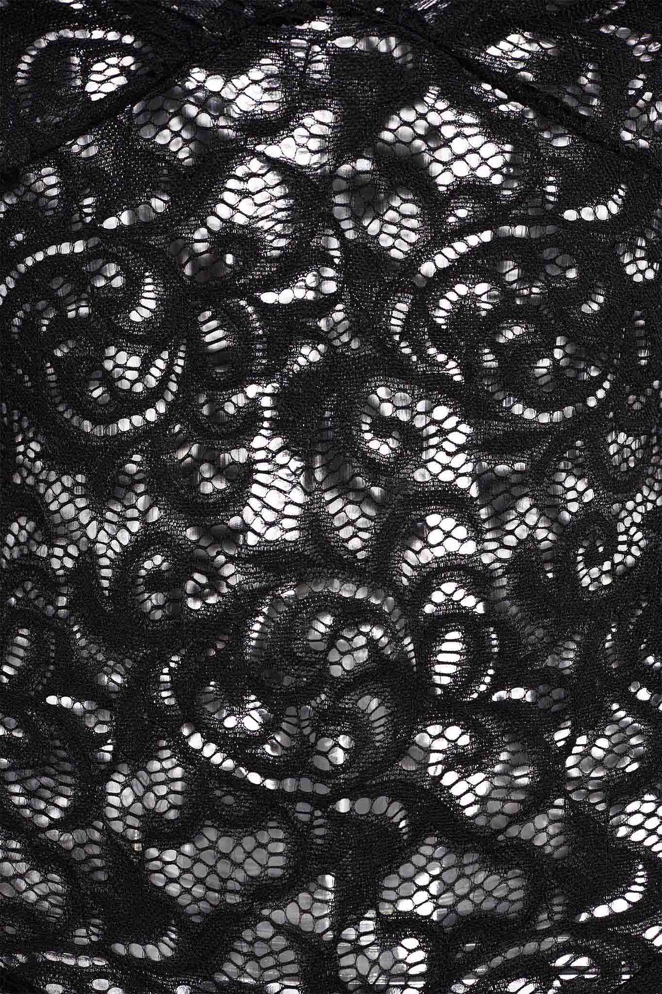 Close-up of the GEMMA ROMPER - BLACK from I.AM.GIA, showcasing its intricate swirling black lace fabric. The lace, true to I.AM.GIA's edgy style, features a mix of both dense and open weave sections creating an elegant, delicate texture. Light filters through the lace, highlighting the detailed design.