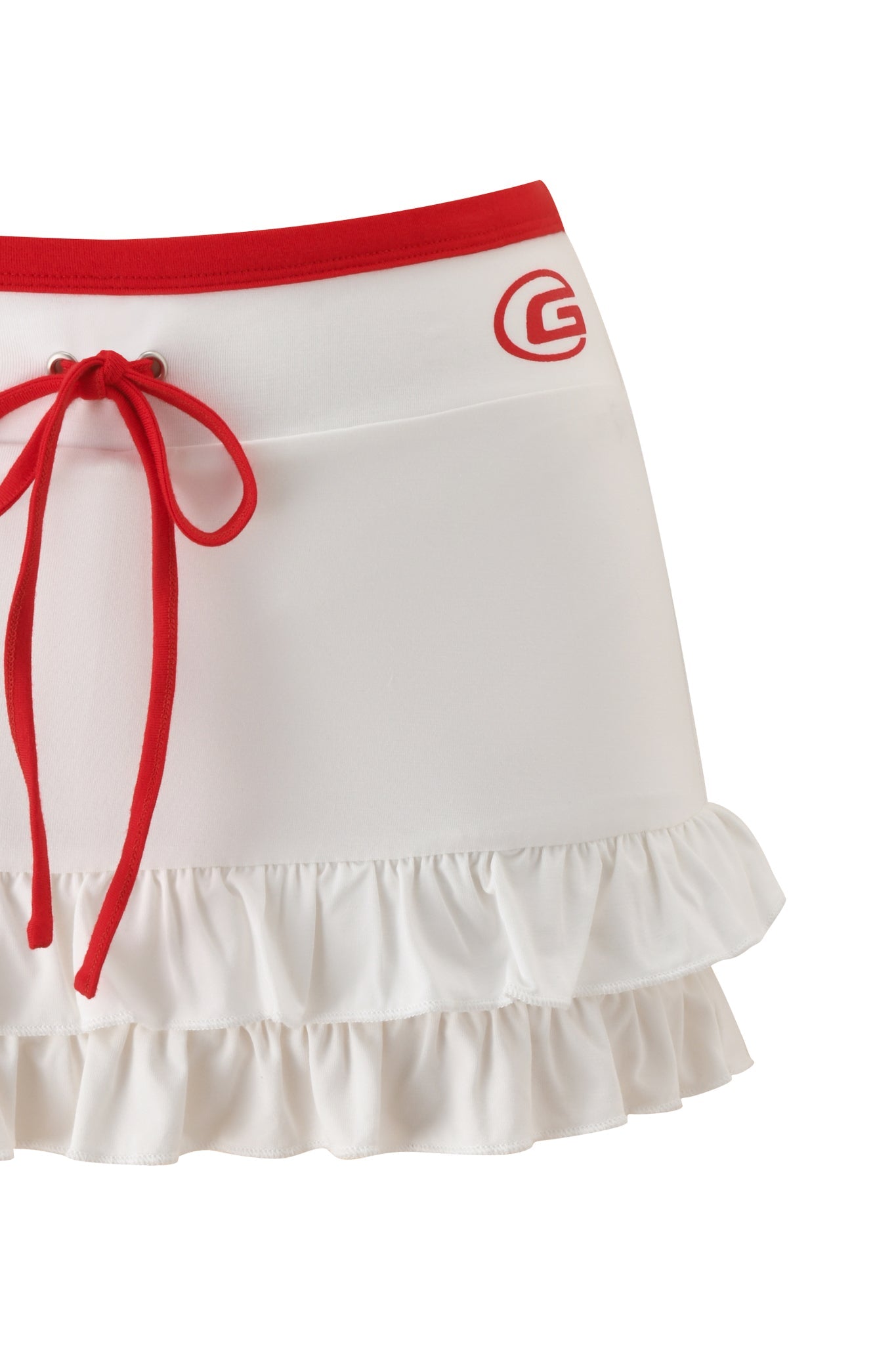 The I.AM.GIA MICHELLE SKORT - WHITE is a micro mini skort featuring layered ruffle hems, a bold red waistband with drawstring bow, and a red "G" logo on the top right side.