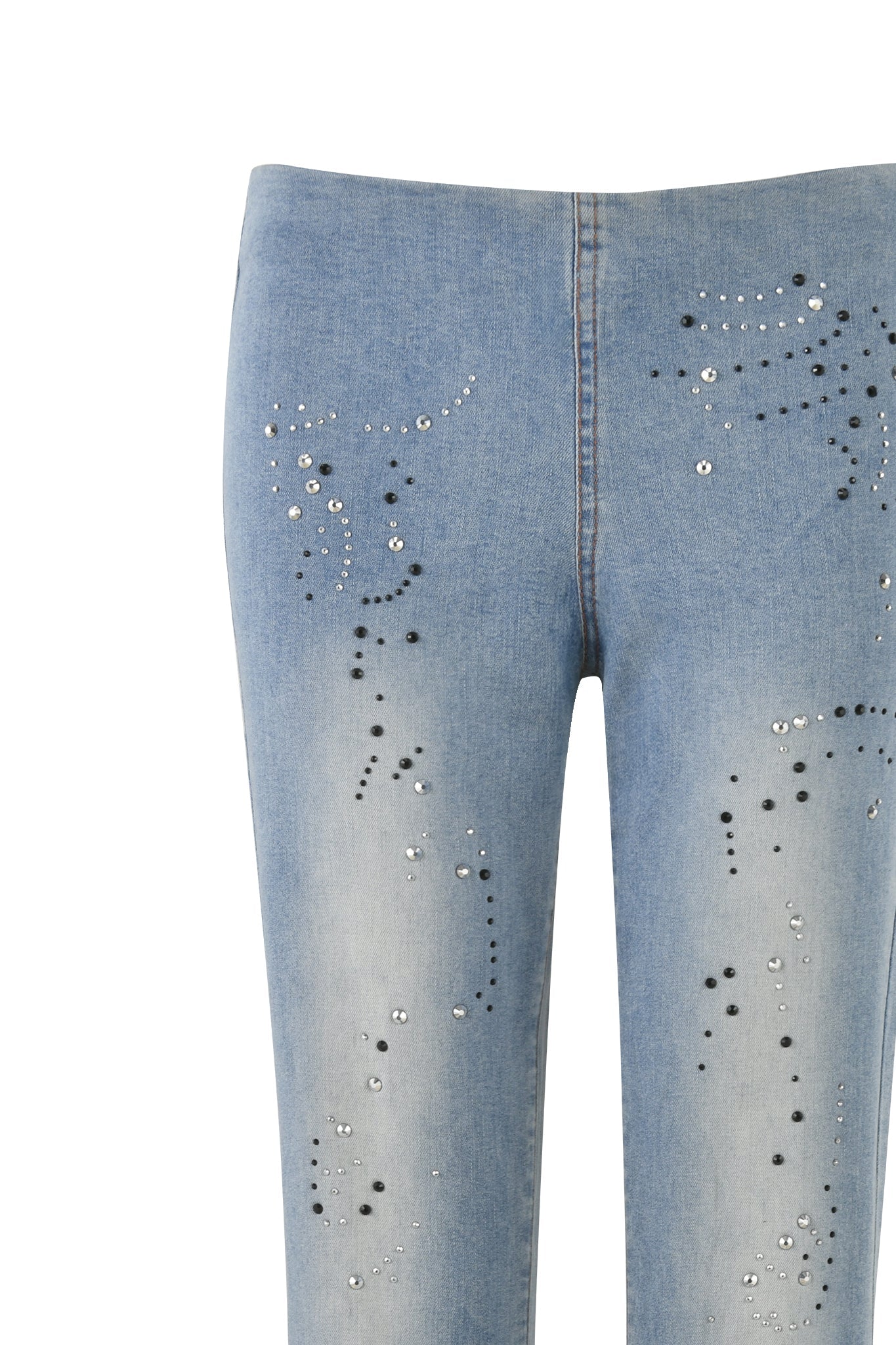 A detailed view of the I.AM.GIA REQUIEM JEAN in Denim Blue, showcasing light blue denim adorned with variously sized black and silver studs arranged in abstract patterns. The jeans feature a faded wash and a hint of diamante embellishment, shown from the waist down to the mid-thigh.