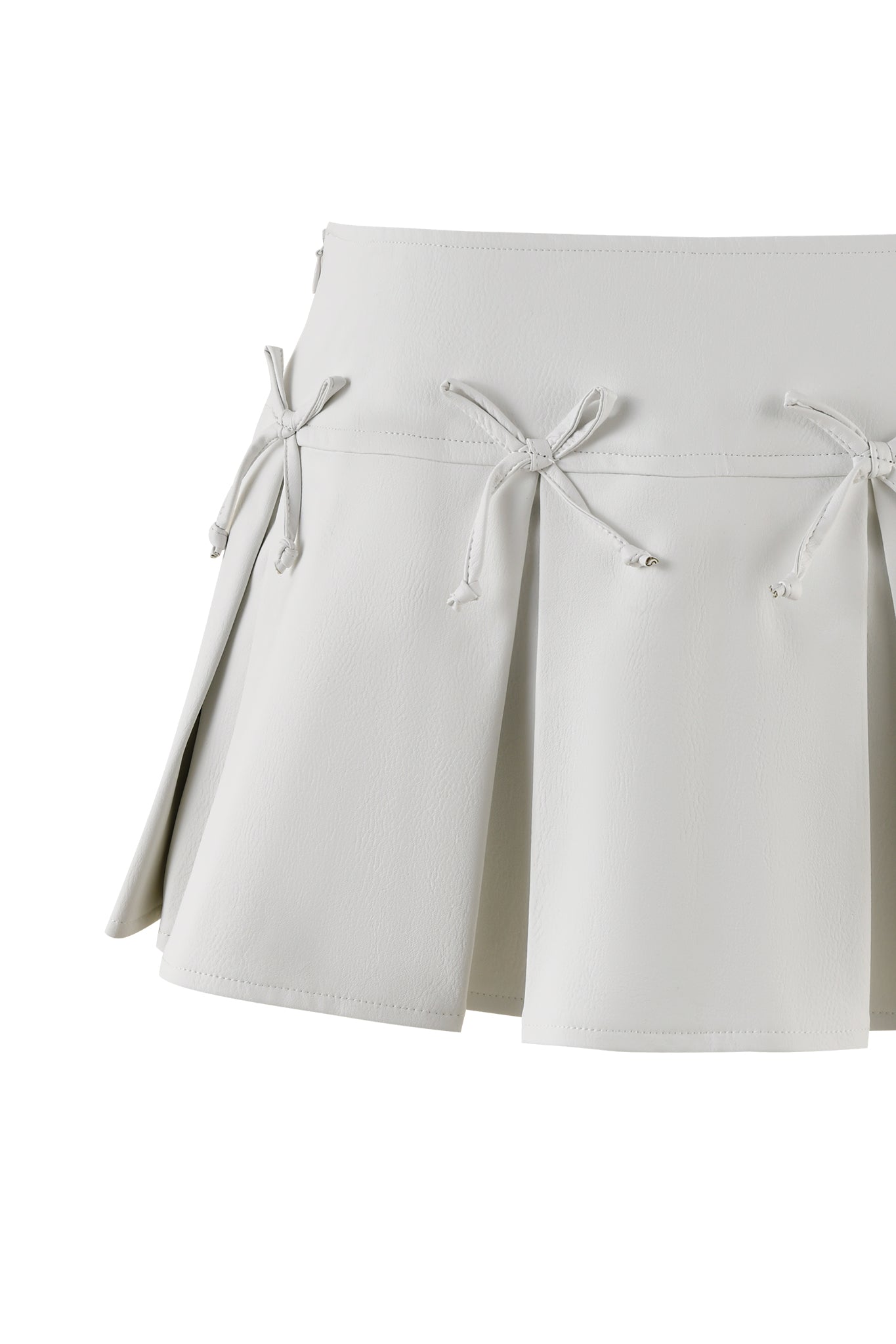 The EVERETTE SKORT - WHITE by I.AM.GIA is a high-waisted pleated skort featuring decorative strings tied in bows on the front. It has a clean, elegant design with a smooth texture, giving it a chic and stylish appearance.