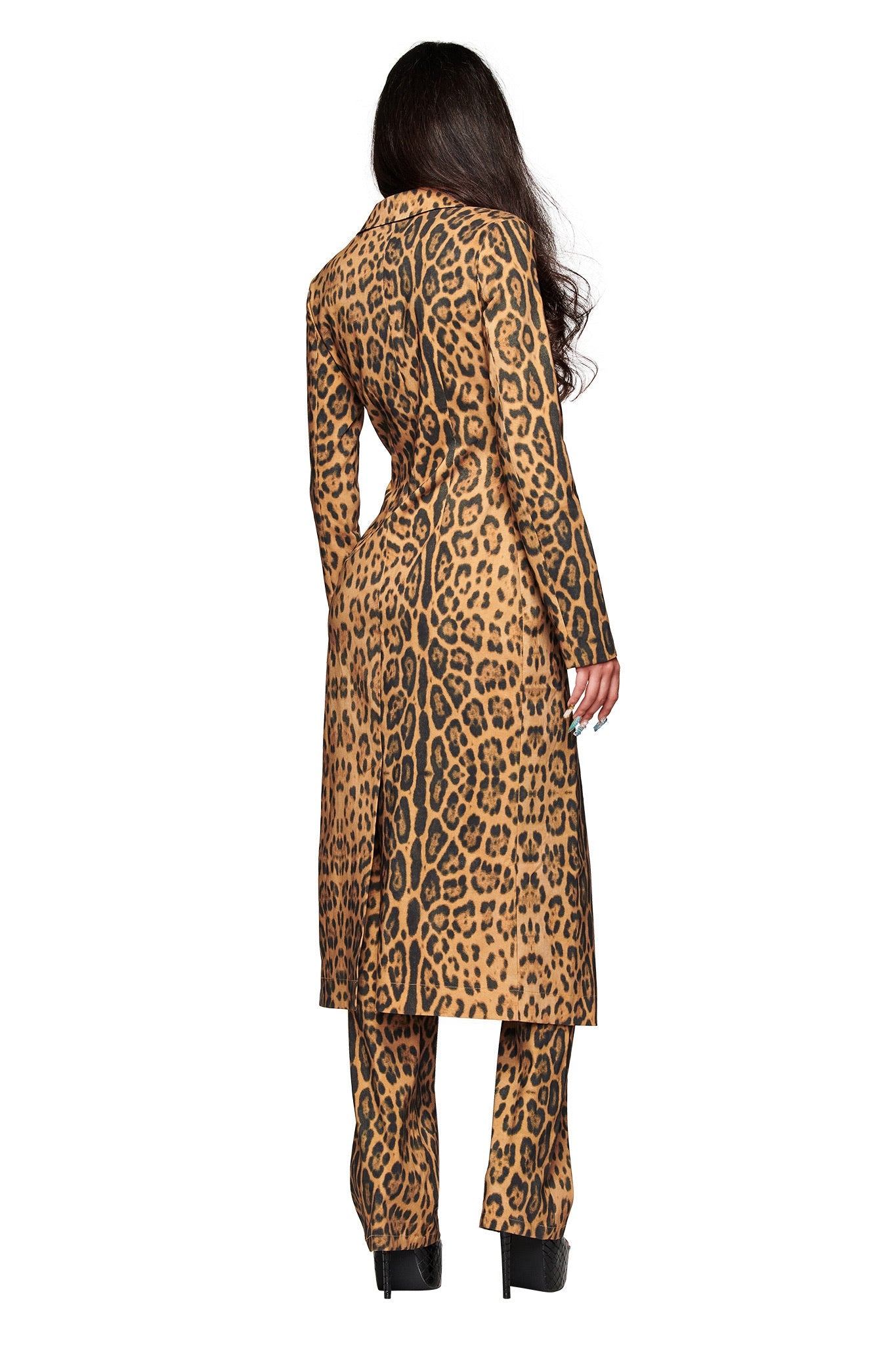 A person with long dark hair faces away, wearing the I.AM.GIA UMA COAT - PANTHERA and matching pants with black platform heels, set against a plain white background.