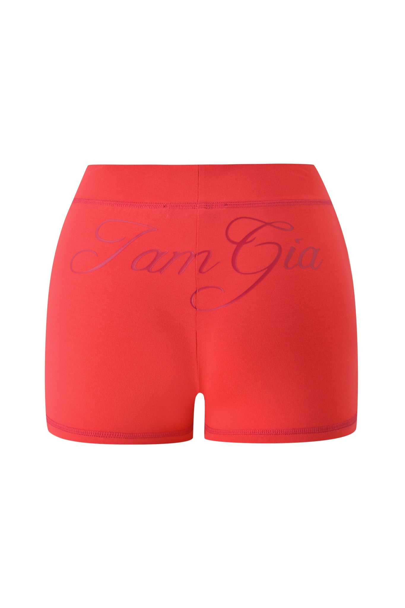 The BLARE SHORT - PAPAYA by I.AM.GIA is a red high-waisted short with an elastic waistband and bold, cursive "I.AM.GIA" printed across the back for a standout look.