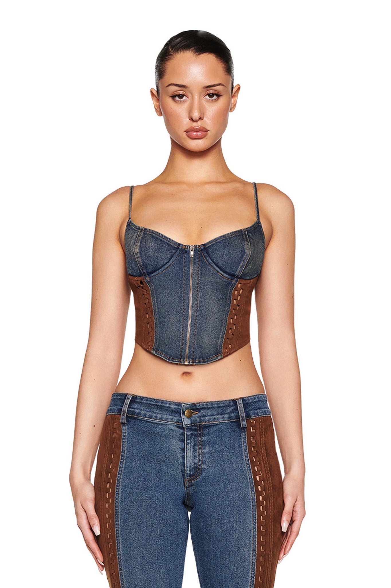A person poses against a white backdrop wearing the I.AM.GIA FORREST BUSTIER in medium wash denim, matched with similar jeans. Their hair is styled in a neat updo that complements the bustier's brown panel accents.