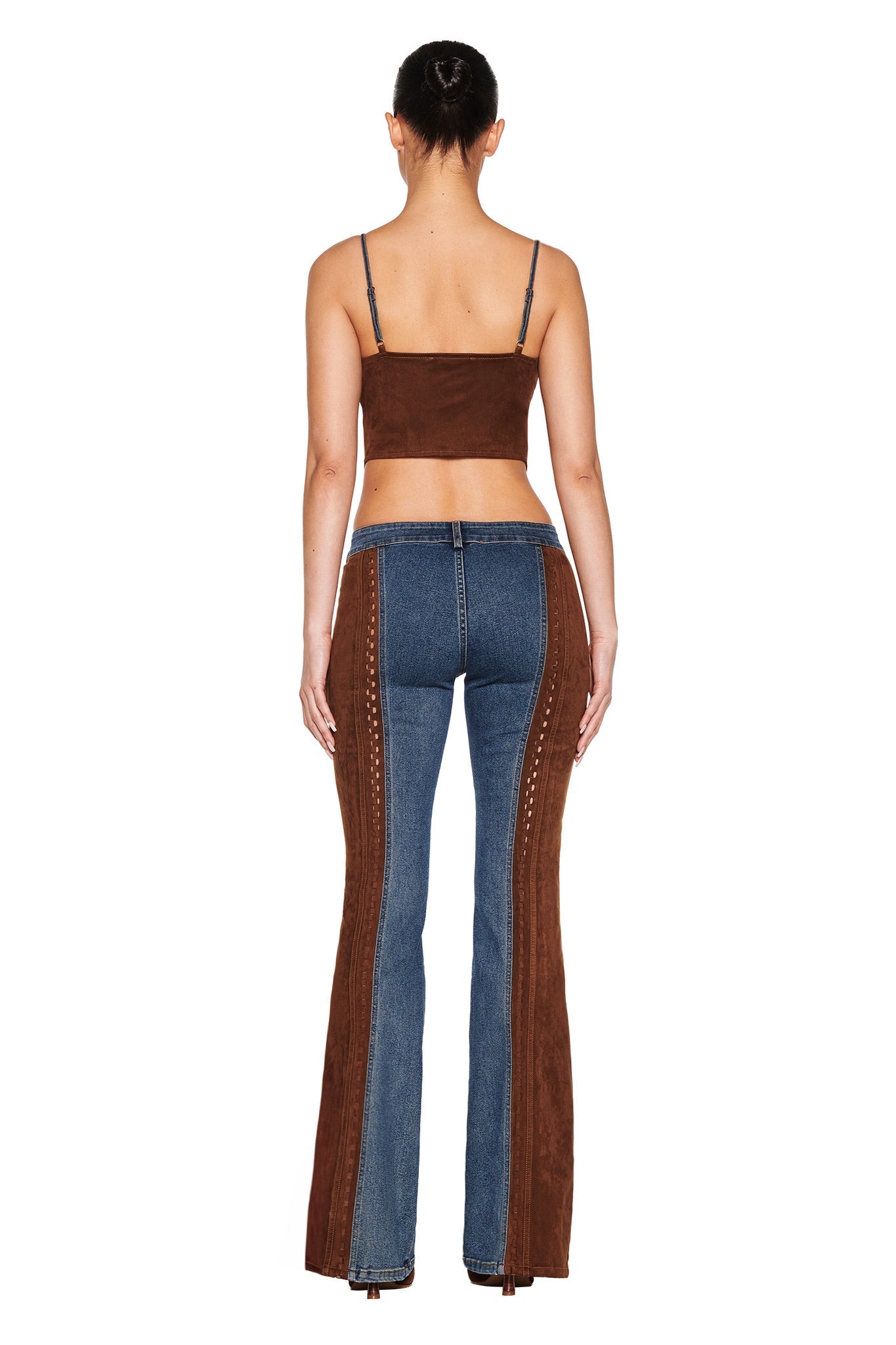 With hair tied up, a person is seen from the back in a brown crop top and I.AM.GIA's FORREST PANT in medium blue wash. The flare jeans feature retro charm with brown suede contrast panels and decorative side stitching.