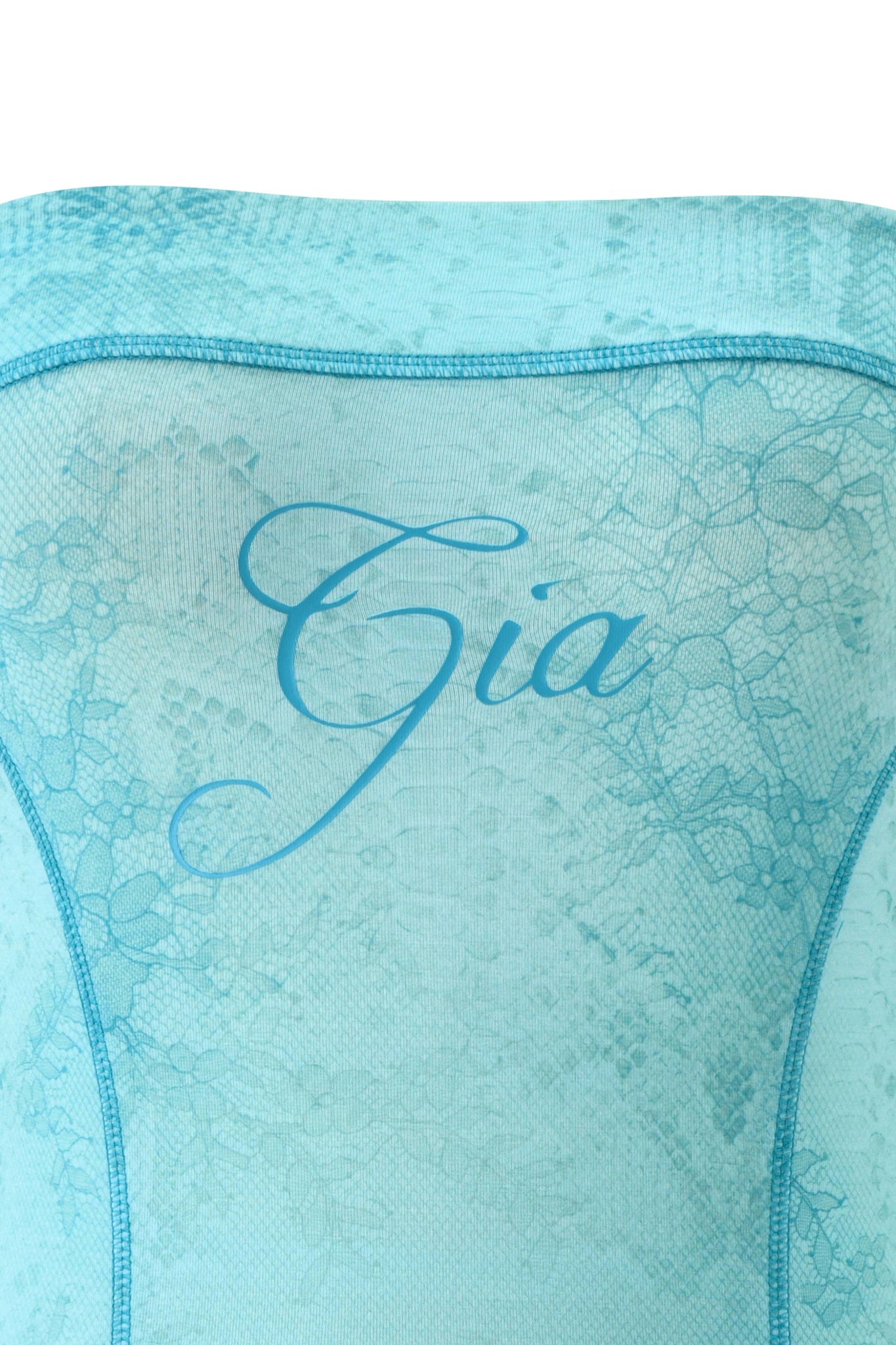 A close-up of light blue lace fabric with a floral pattern, echoing the BLARE TUBE MINI DRESS - TEAL SERPENTINE by I.AM.GIA, with "Gia" elegantly scripted across the center.