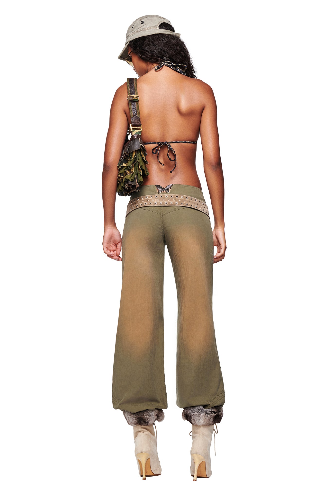 A woman faces away, wearing the I.AM.GIA SEQUOIA PANT in army green with a bikini top, high heels, a bucket hat, and a shoulder bag. A butterfly tattoo is seen on her lower back.