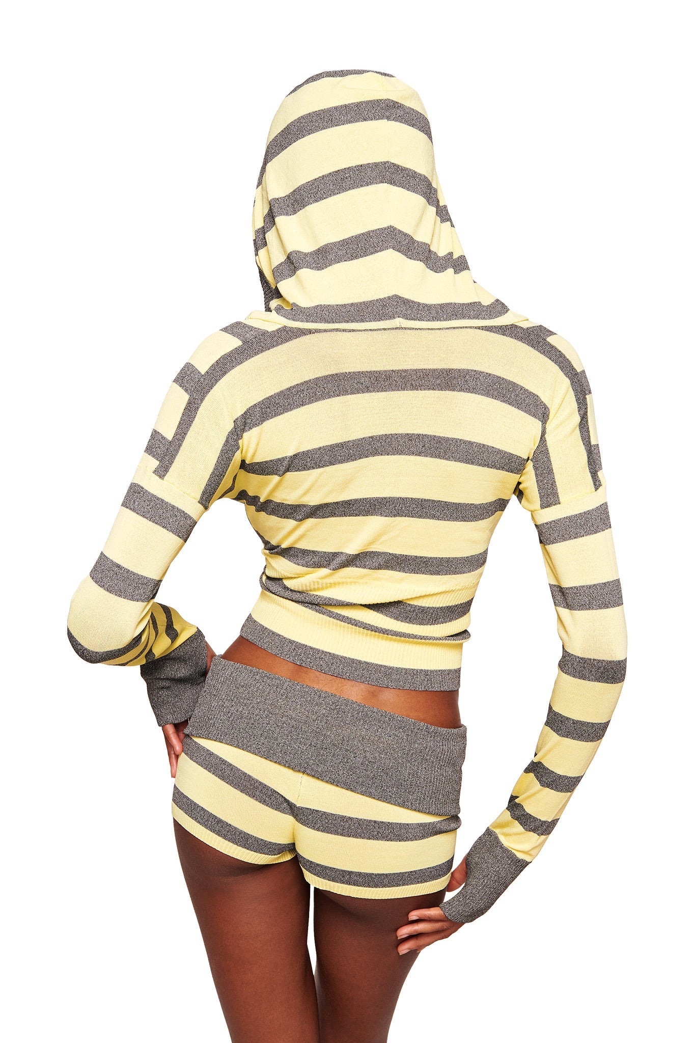 A person faces away from the camera, wearing the I.AM.GIA SUZI SHORT in Yellow and Grey Stripe, paired with a matching striped hoodie with the hood up and hand on hip.